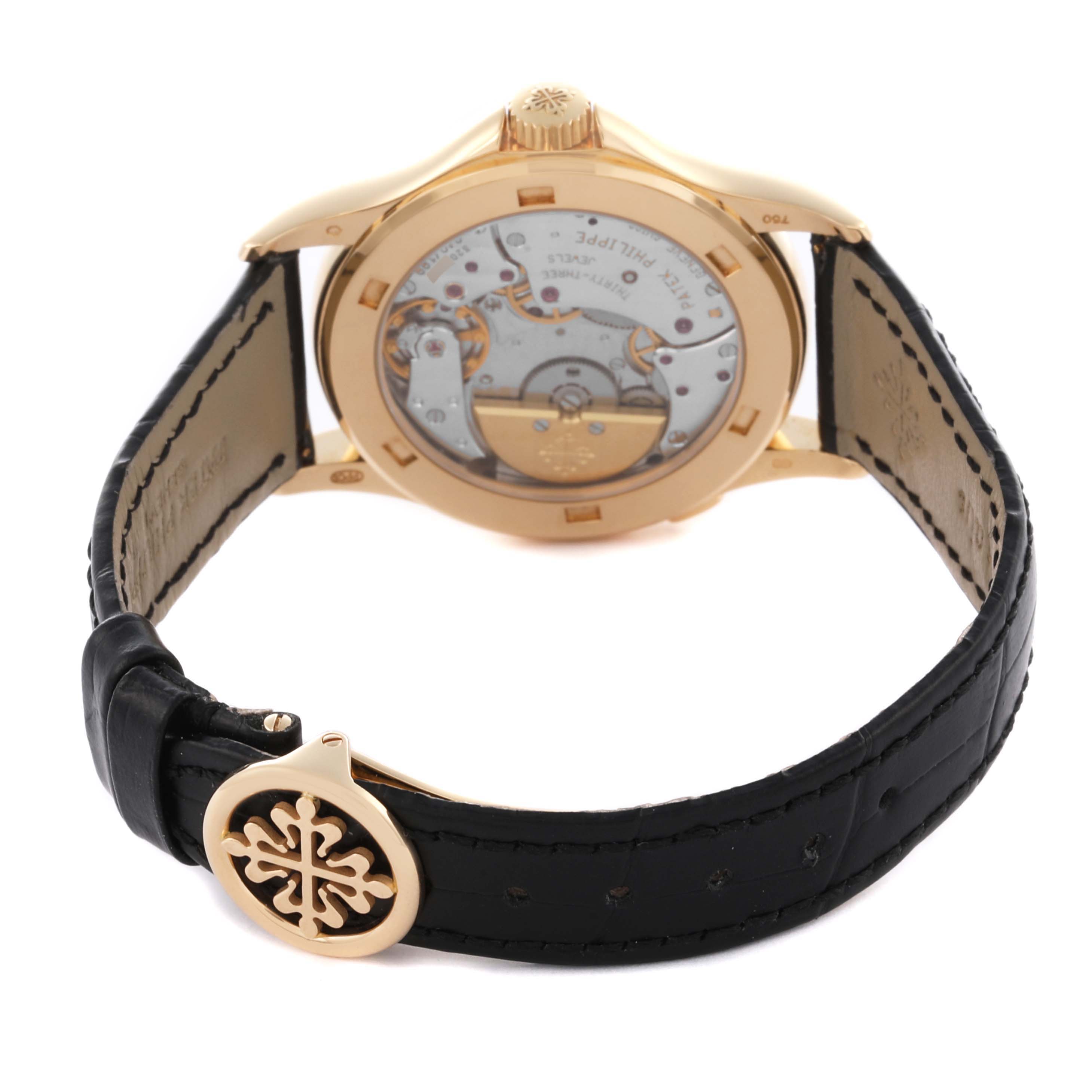 The Patek Philippe Complications 5110J-001 Men's Yellow Gold Silver Dial 5110J-001 Men's Yellow Gold Silver Dial watch is shown from the back, highlighting the movement and gold case, with a view of the strap and clasp.