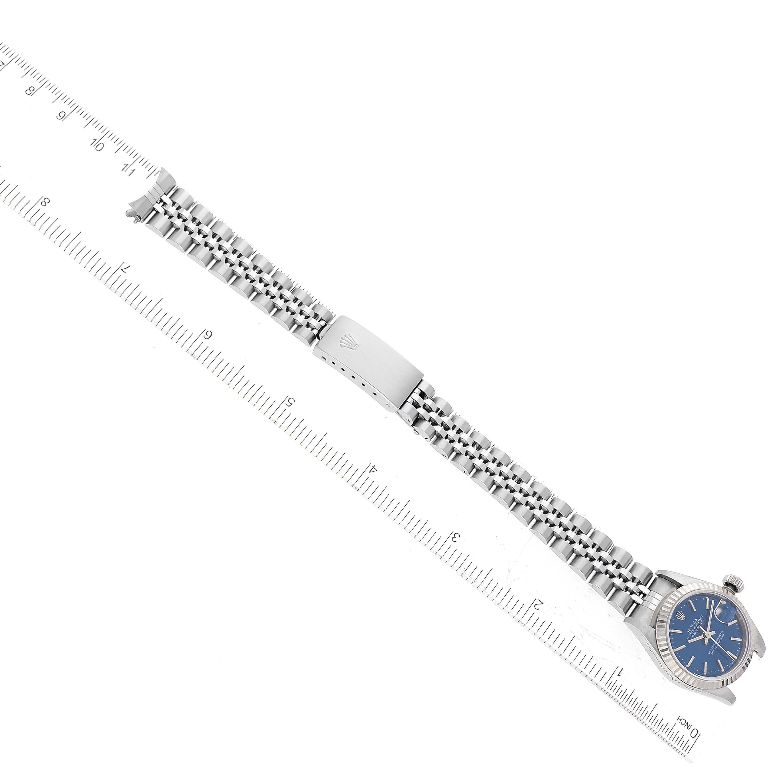The image shows a Rolex Datejust 69174 Women's Stainless Steel Blue Dial 69174 Women's Stainless Steel Blue Dial watch laid flat with a stainless steel jubilee bracelet and blue dial, aligned next to a ruler.