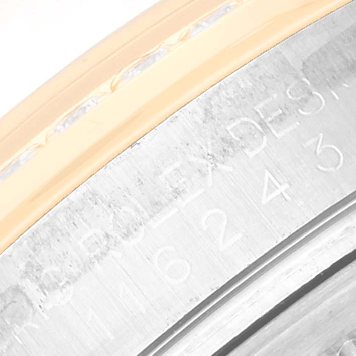 This image shows a close-up of the bezel and part of the engraved case of a Rolex Datejust 116243 Men's Steel and Gold (two tone) Champagne Dial 116243 Men's Steel and Gold (two tone) Champagne Dial watch.