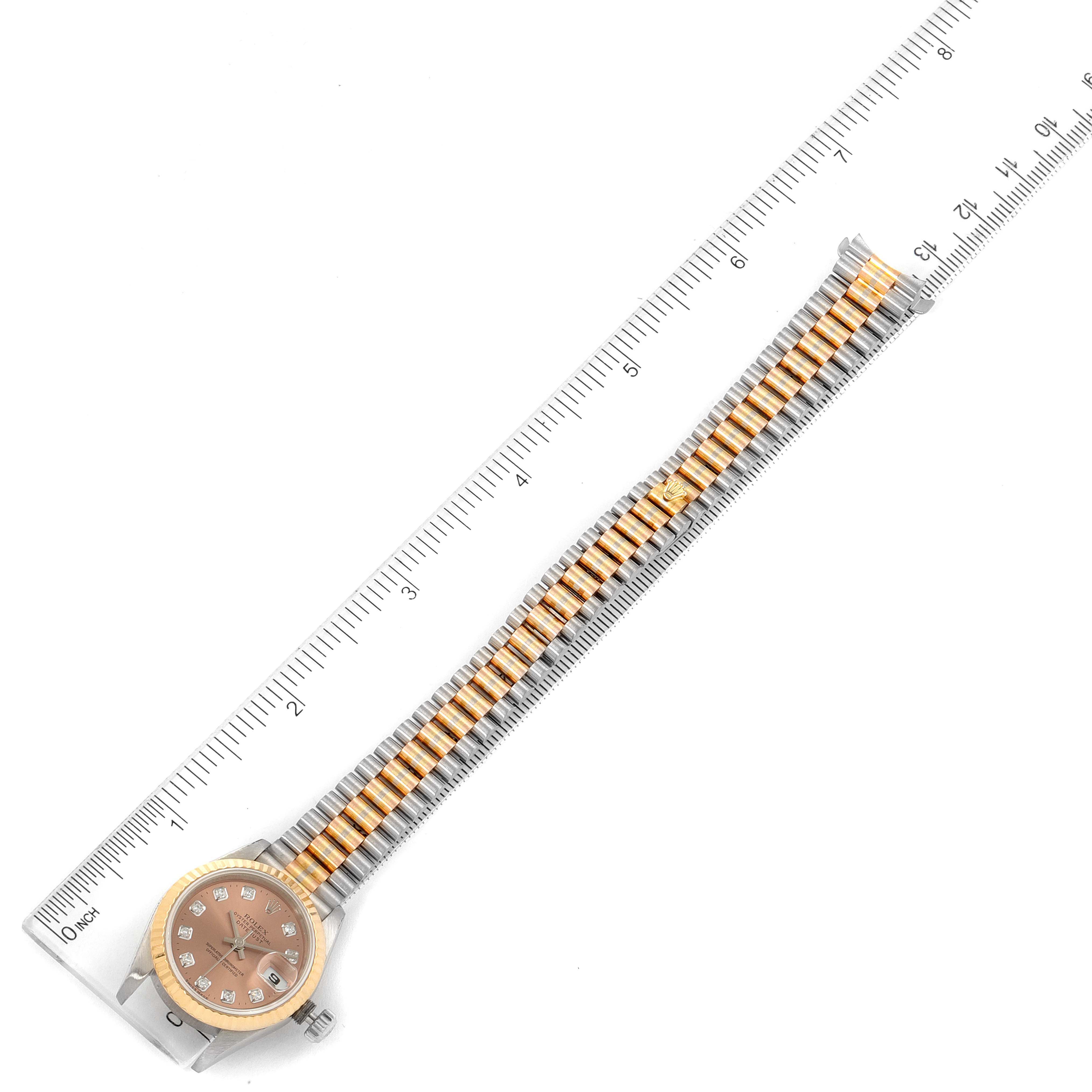 This image shows the Rolex President 69179 Women's White Gold Brown Dial 69179 Women's White Gold Brown Dial model watch laid flat with a measuring ruler alongside it.