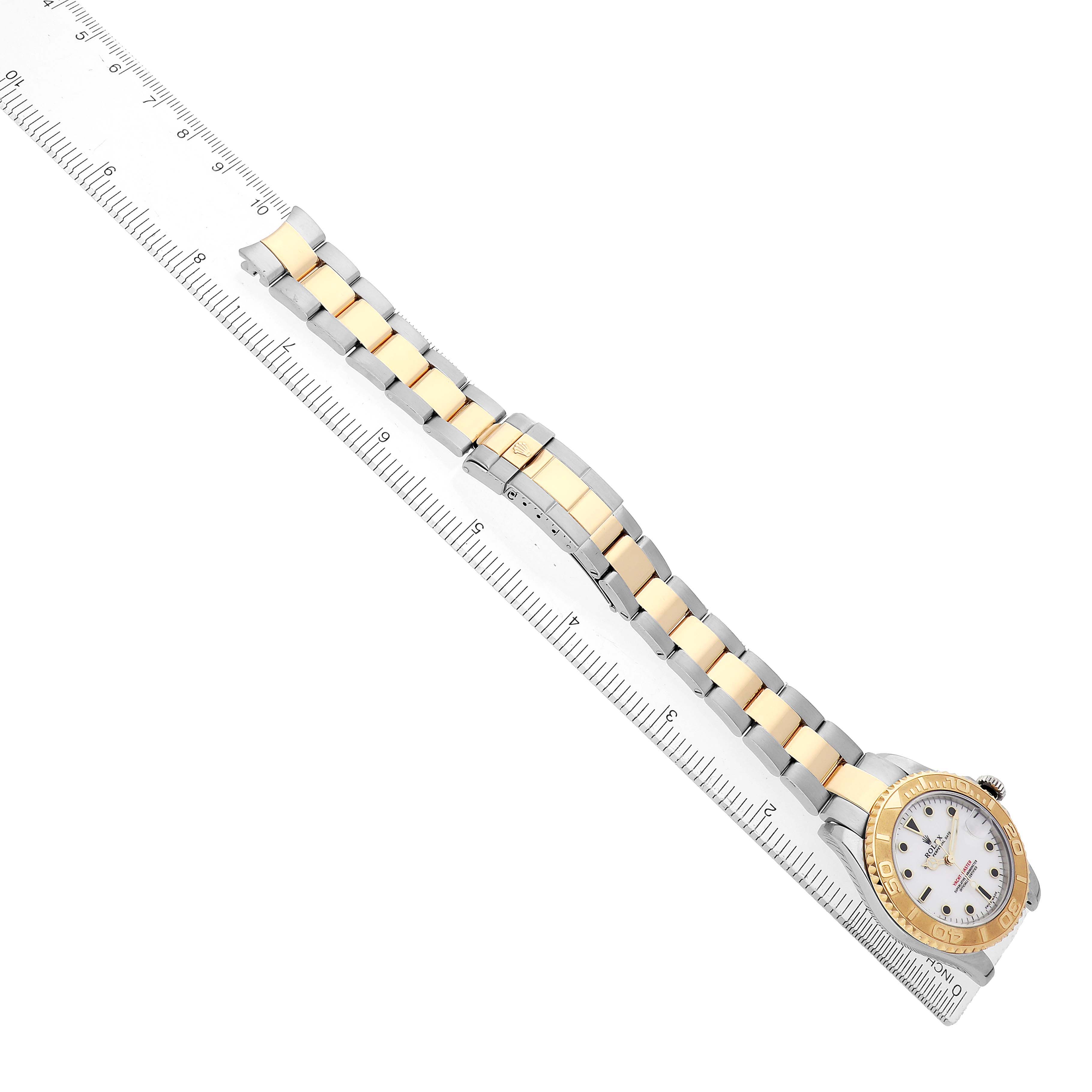 The image shows a side view of a Rolex Yacht-Master 168623 Men's Steel and Gold (two tone) White Dial watch, highlighting its gold and silver bracelet and bezel, placed on a ruler.