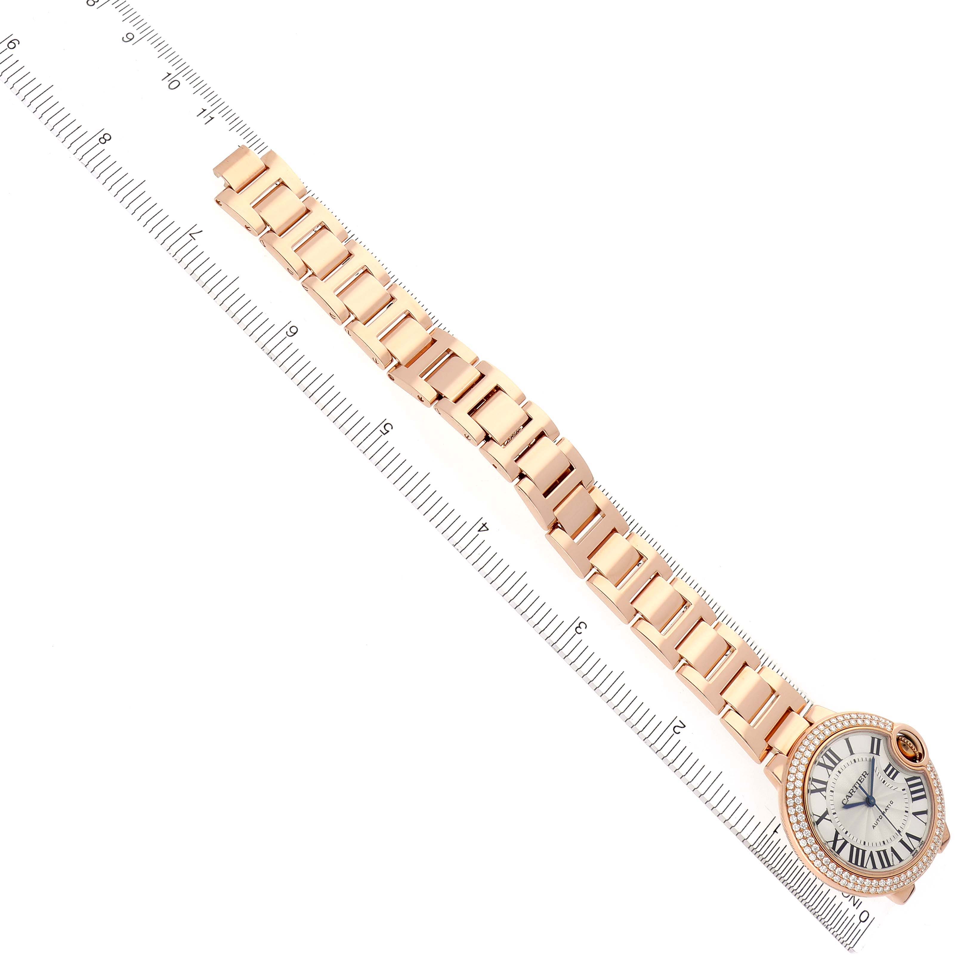 The Cartier Ballon Bleu WE902064 Men
s Rose Gold Silver Dial WE902064 Men
s Rose Gold Silver Dial watch is shown from a top view, displaying the full bracelet and face against a ruler for scale.