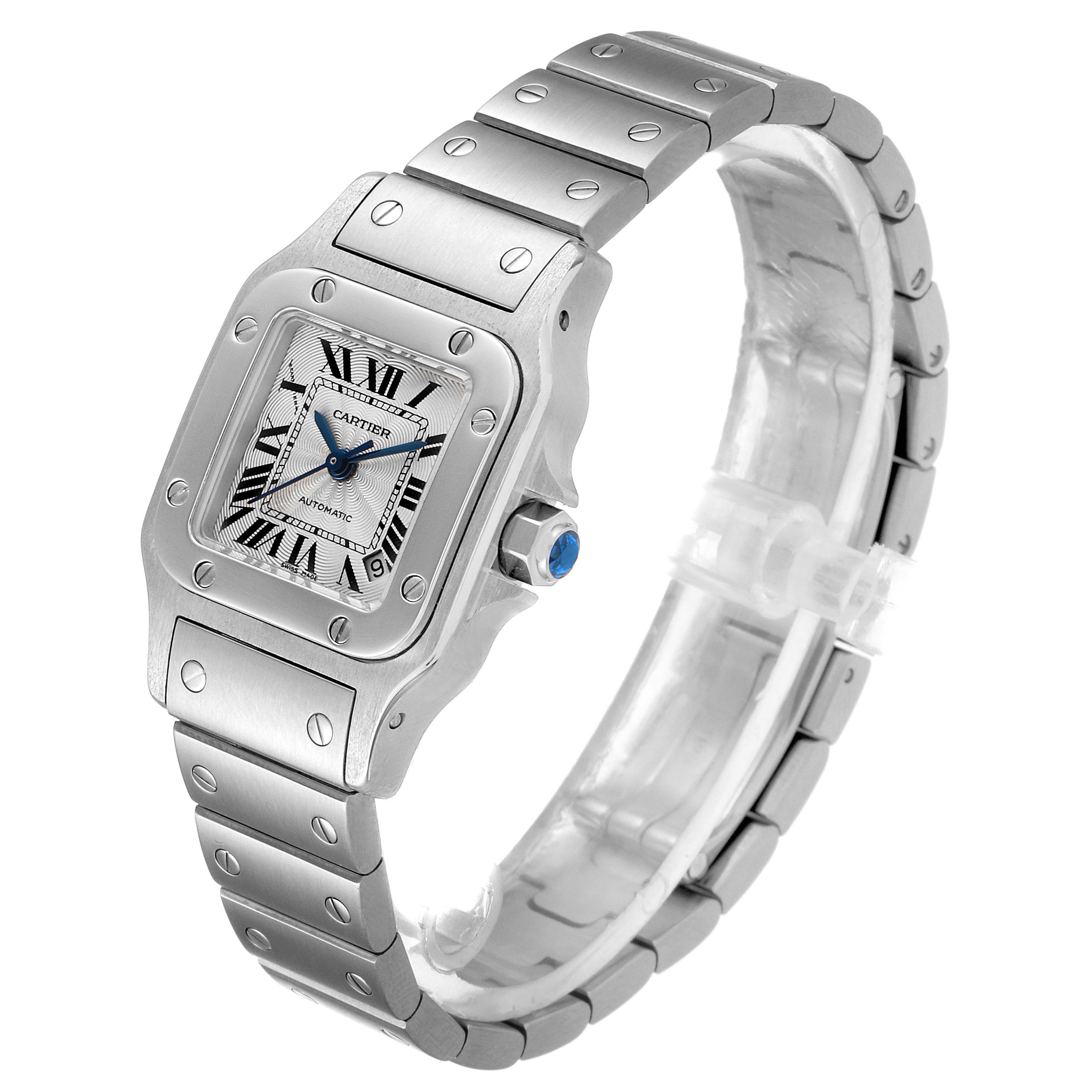 The watch is a Santos model by Cartier shown at an angle highlighting the face, bezel, bracelet, and crown with a blue gem.