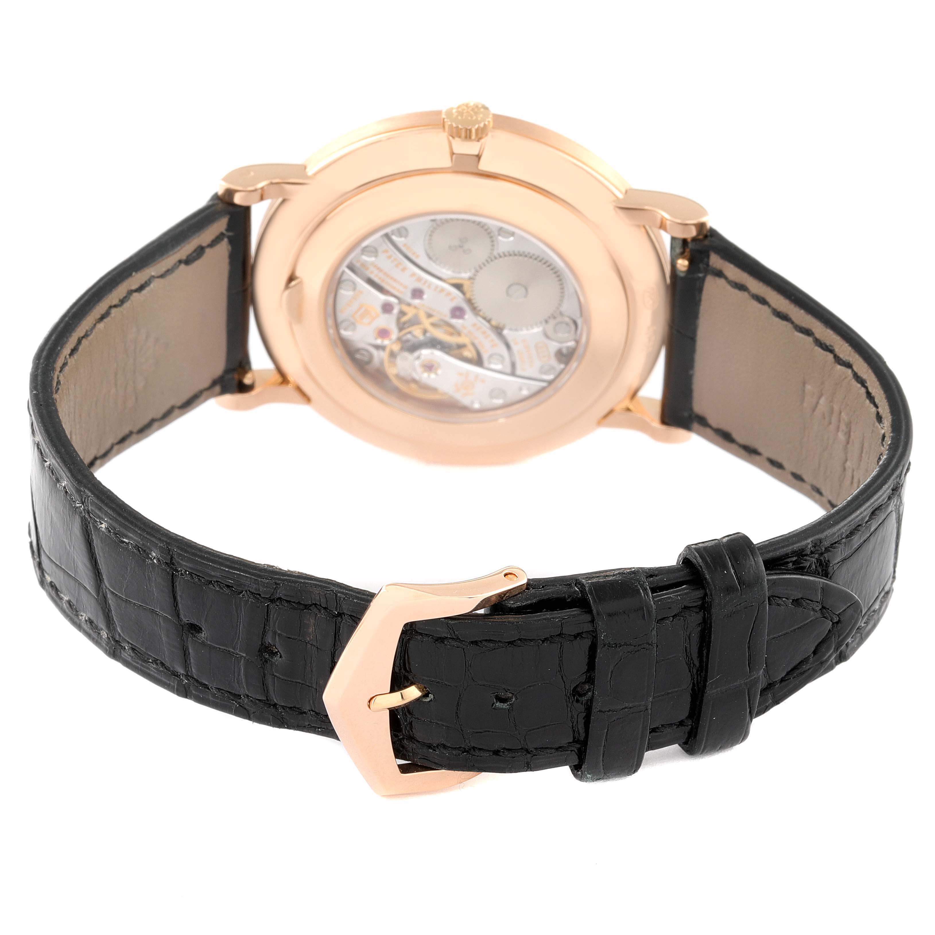 The image shows the back of a Patek Philippe Calatrava 5116R Men
s Rose Gold White Dial 5116R Men
s Rose Gold White Dial watch with its open case back and black leather strap.