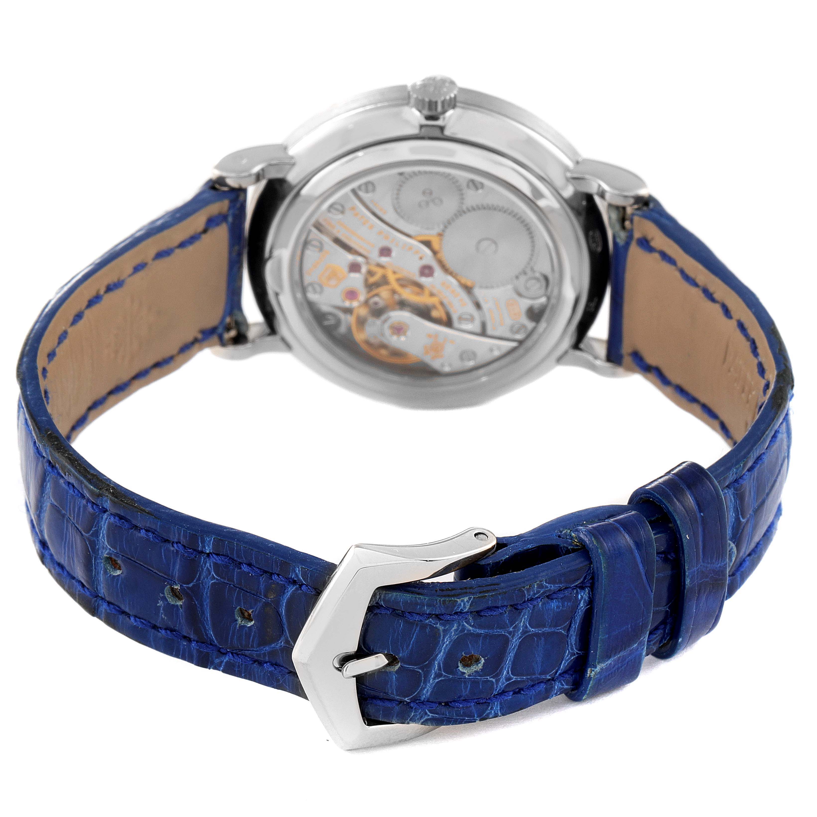 The image shows the back view of a Patek Philippe Calatrava 7120G Women's White Gold Beige Dial 7120G Women's White Gold Beige Dial watch, displaying its movement and blue leather strap with buckle.