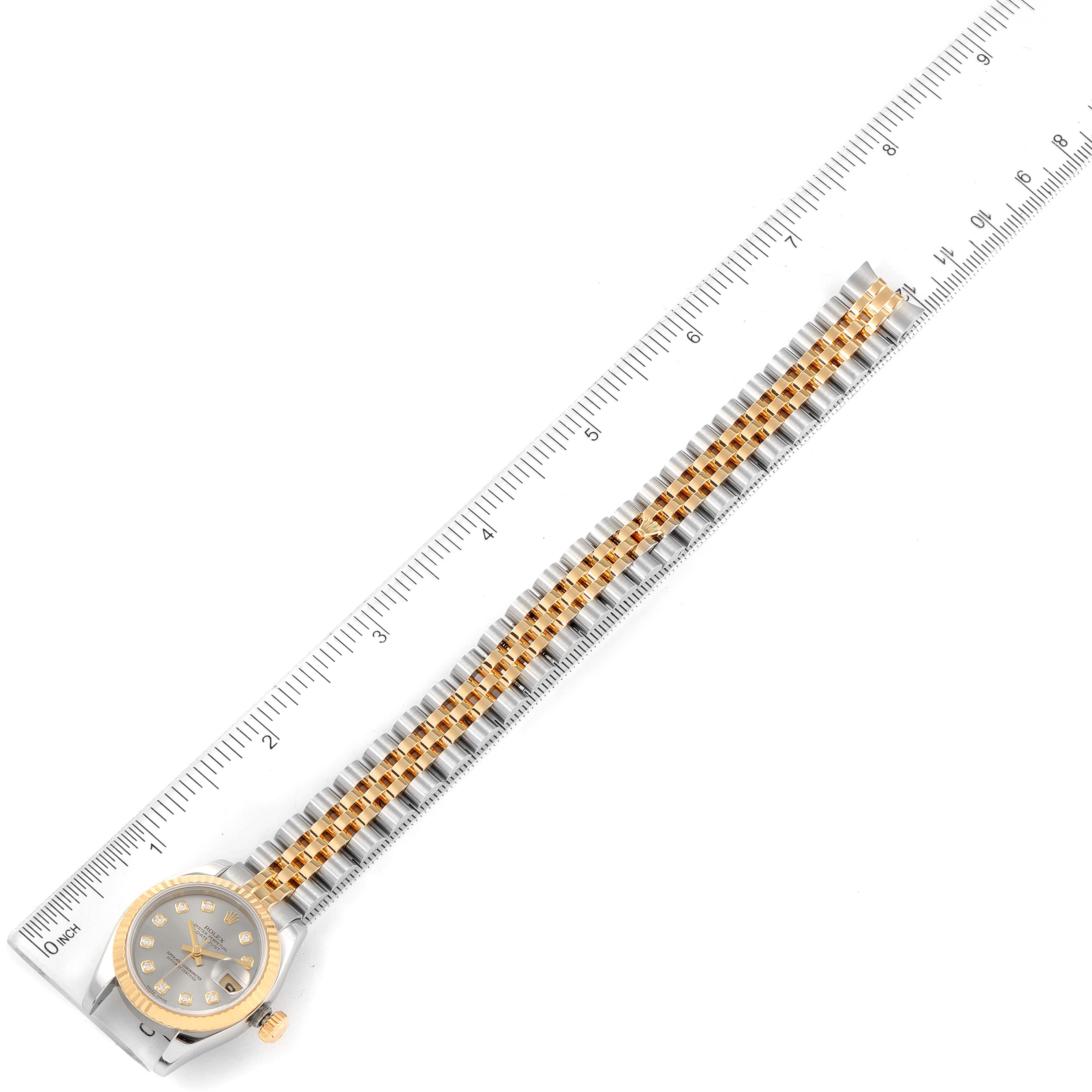 The image shows a Rolex Datejust 179173 Women
s Steel and Gold (two tone) Grey Dial 179173 Women
s Steel and Gold (two tone) Grey Dial watch laid flat along a ruler, displaying its face and full bracelet.
