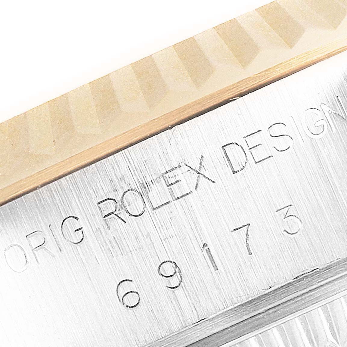 This close-up angle of the Rolex Datejust 69173 Women
s Steel and Gold (two tone) Champagne Dial 69173 Women
s Steel and Gold (two tone) Champagne Dial watch shows the fluted bezel and the engraved serial and model numbers on the case.