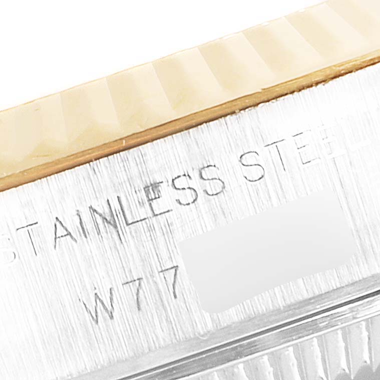 The image shows a close-up of the casing side of a Rolex Datejust 69173 Women
s Steel and Gold (two tone) Champagne Dial 69173 Women
s Steel and Gold (two tone) Champagne Dial watch, displaying part of the fluted bezel and inscribed text "STAINLESS STEEL".