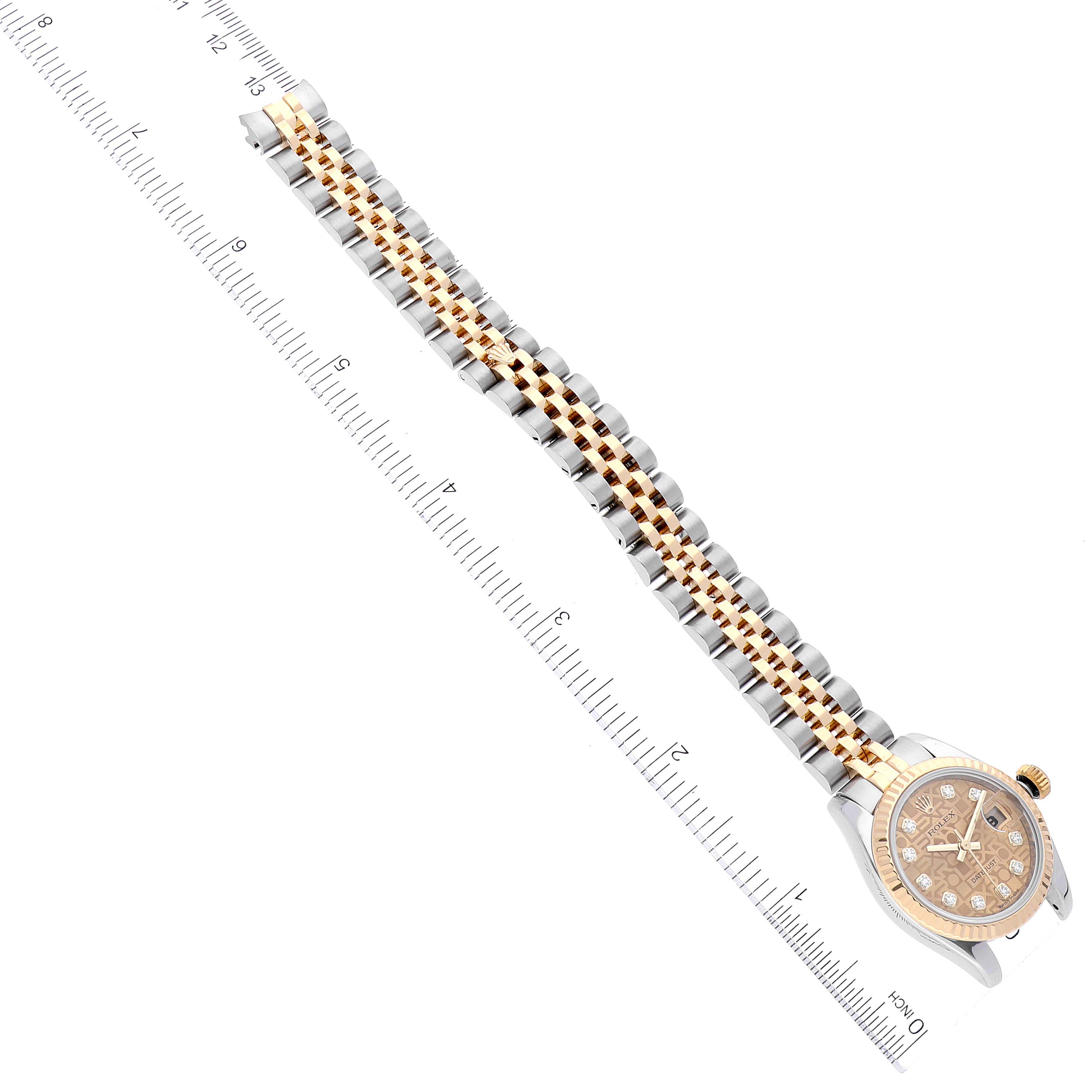 The image shows a gold-and-silver Rolex Datejust 179173 Women's Steel and Gold (two tone) Champagne Dial 179173 Women's Steel and Gold (two tone) Champagne Dial watch placed diagonally next to a ruler, highlighting its bracelet and face.