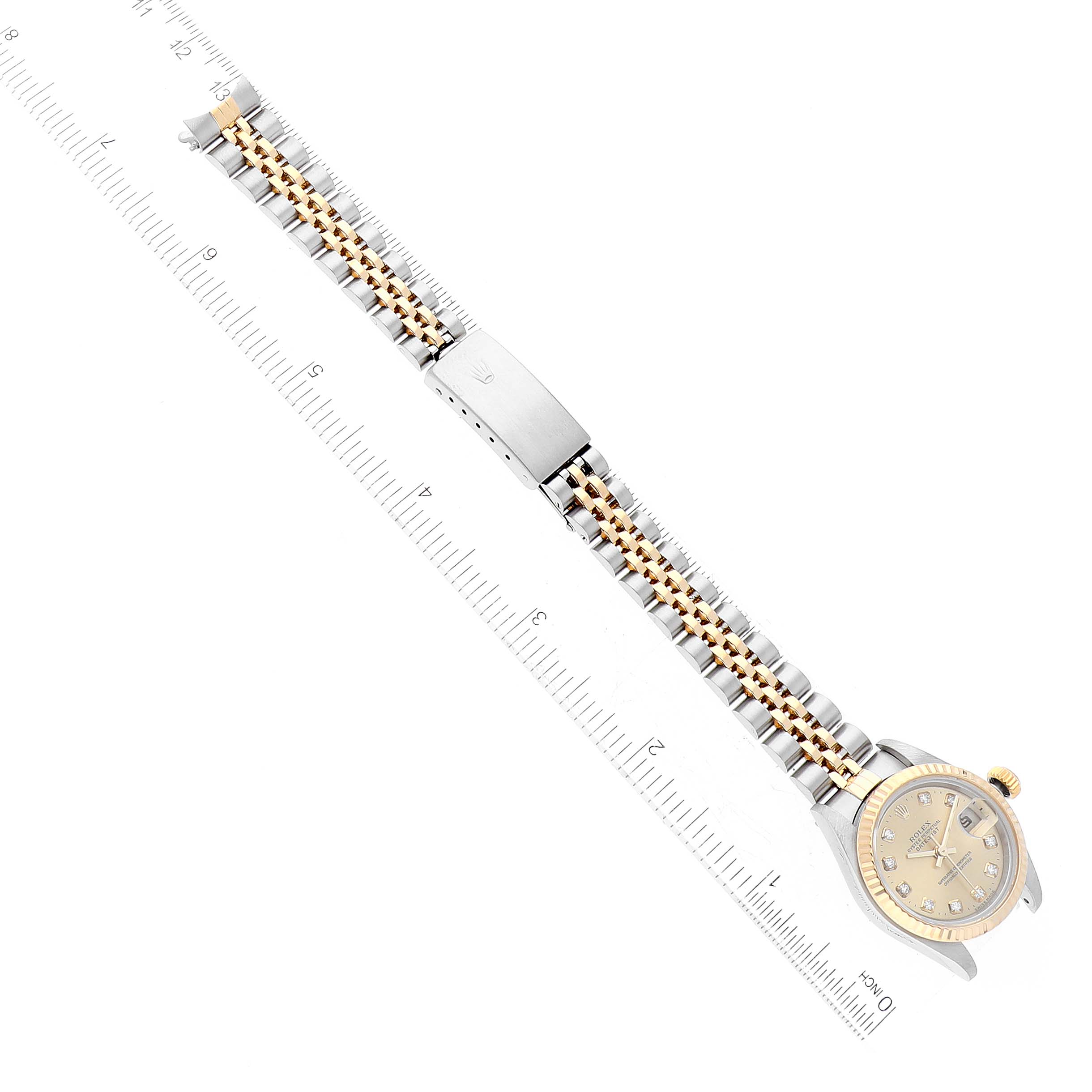 This image shows a bird's-eye view of a Rolex Datejust 79173G Women's Steel and Gold (two tone) Champagne Dial 79173G Women's Steel and Gold (two tone) Champagne Dial watch, displaying the face, bracelet, and clasp alongside a ruler.