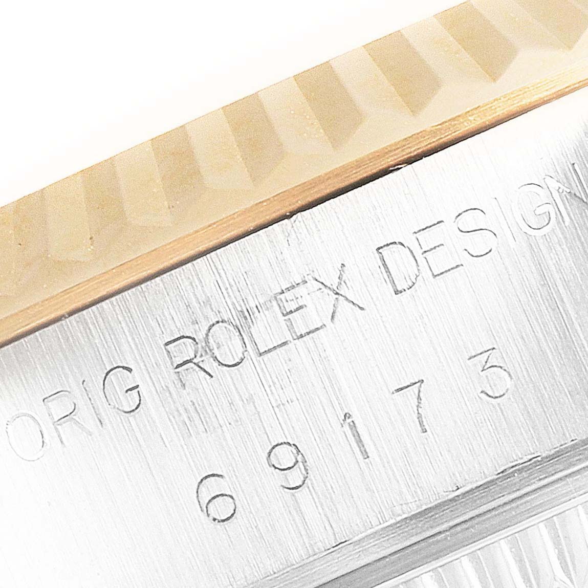 This close-up image of a Rolex Datejust 69173 Women
s Steel and Gold (two tone) Champagne Dial 69173 Women
s Steel and Gold (two tone) Champagne Dial watch shows part of the fluted bezel and engraved case.