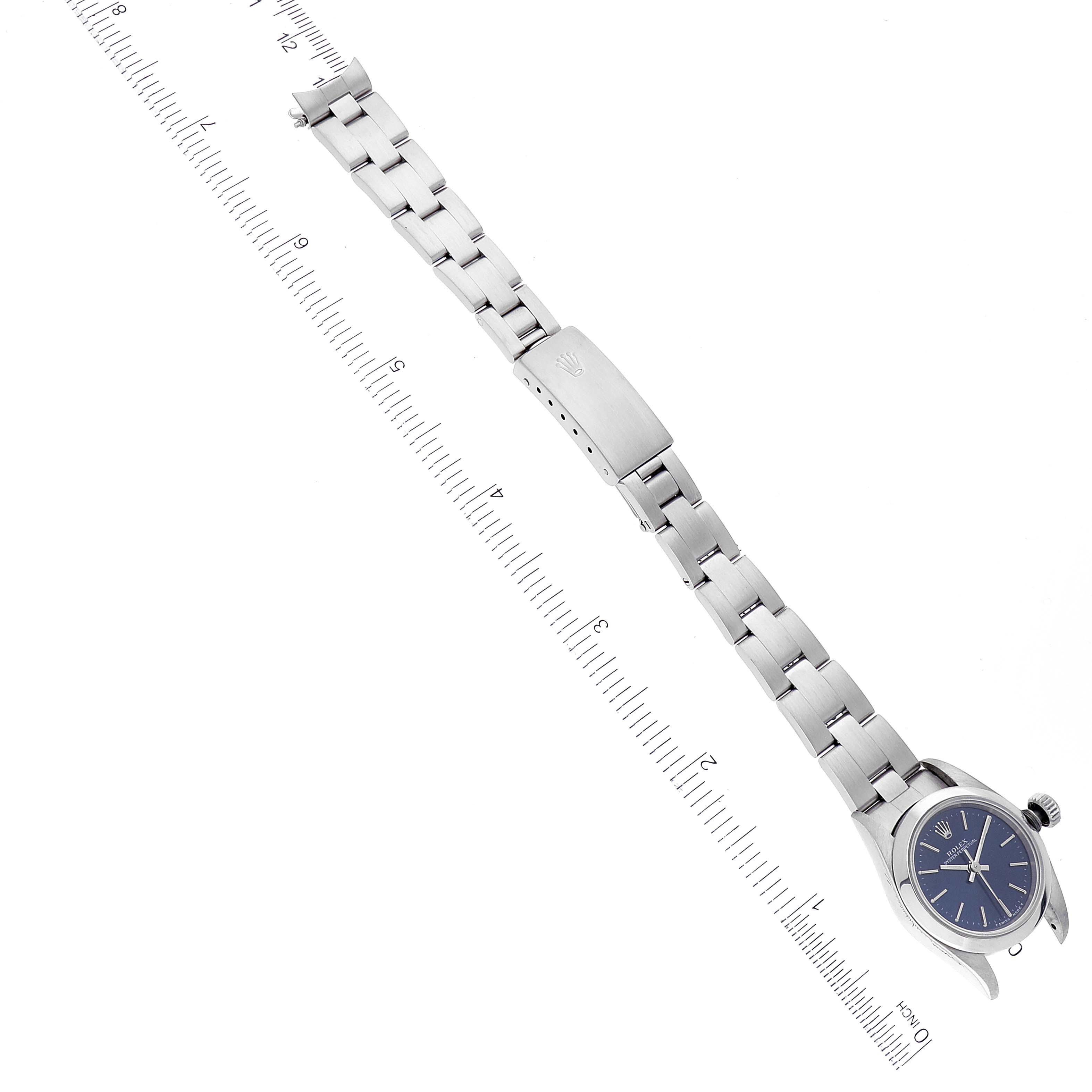 The image shows an Oyster Perpetual Rolex watch from a top-down angle, featuring its full bracelet and partially displayed case and blue dial.