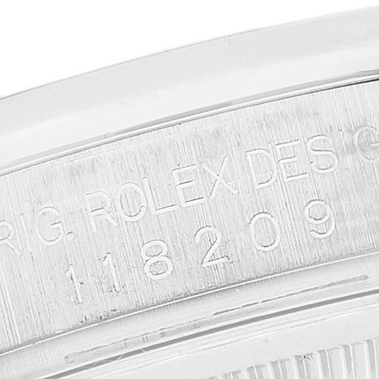 The image shows an angled close-up of the engraved serial number on a Rolex President 118209 Men's White Gold Silver Dial 118209 Men's White Gold Silver Dial model watch.