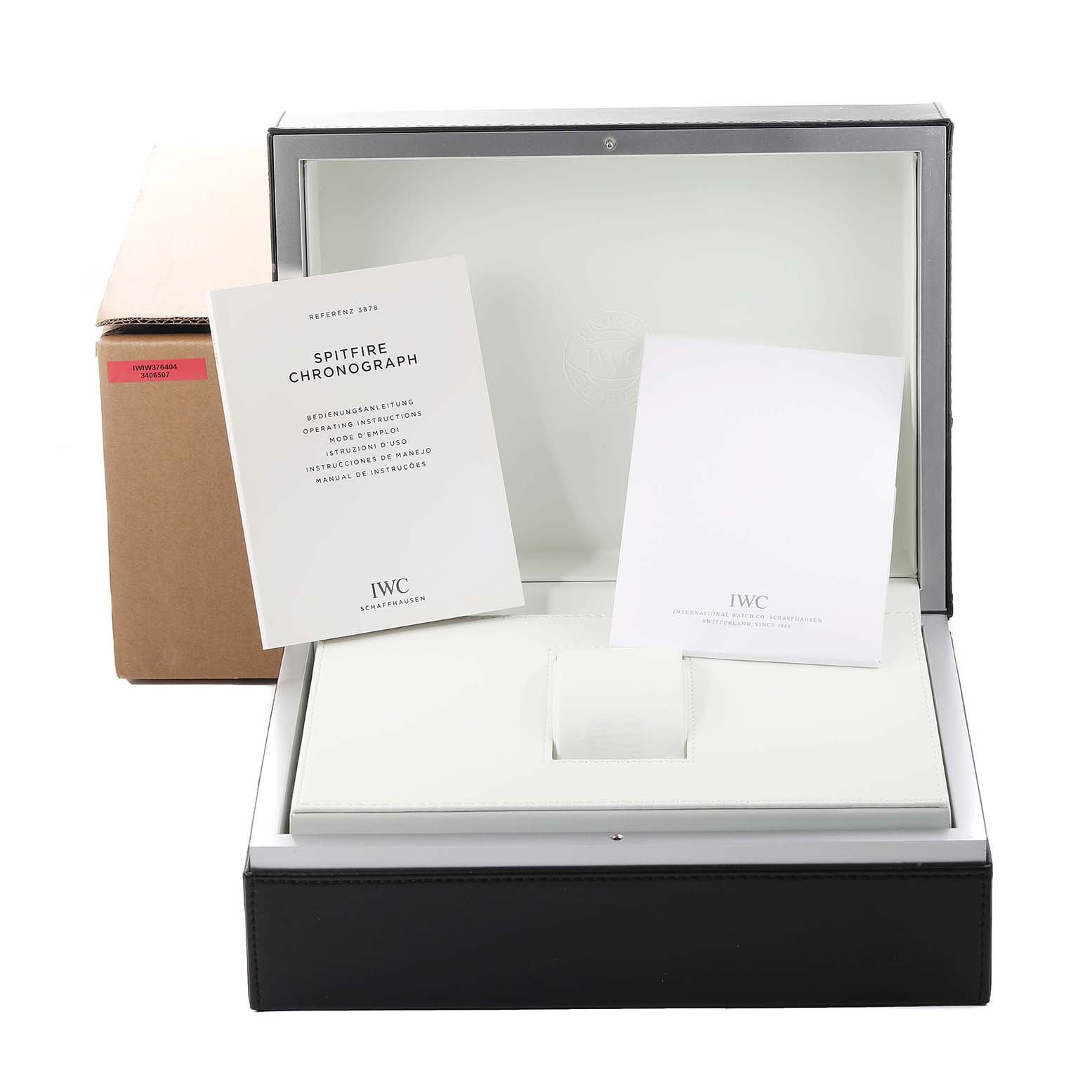 The image shows the open packaging for an IWC Pilot IW387809 Men's Stainless Steel Silver Dial IW387809 Men's Stainless Steel Silver Dial Spitfire Chronograph, including the box, cushion, and manuals.