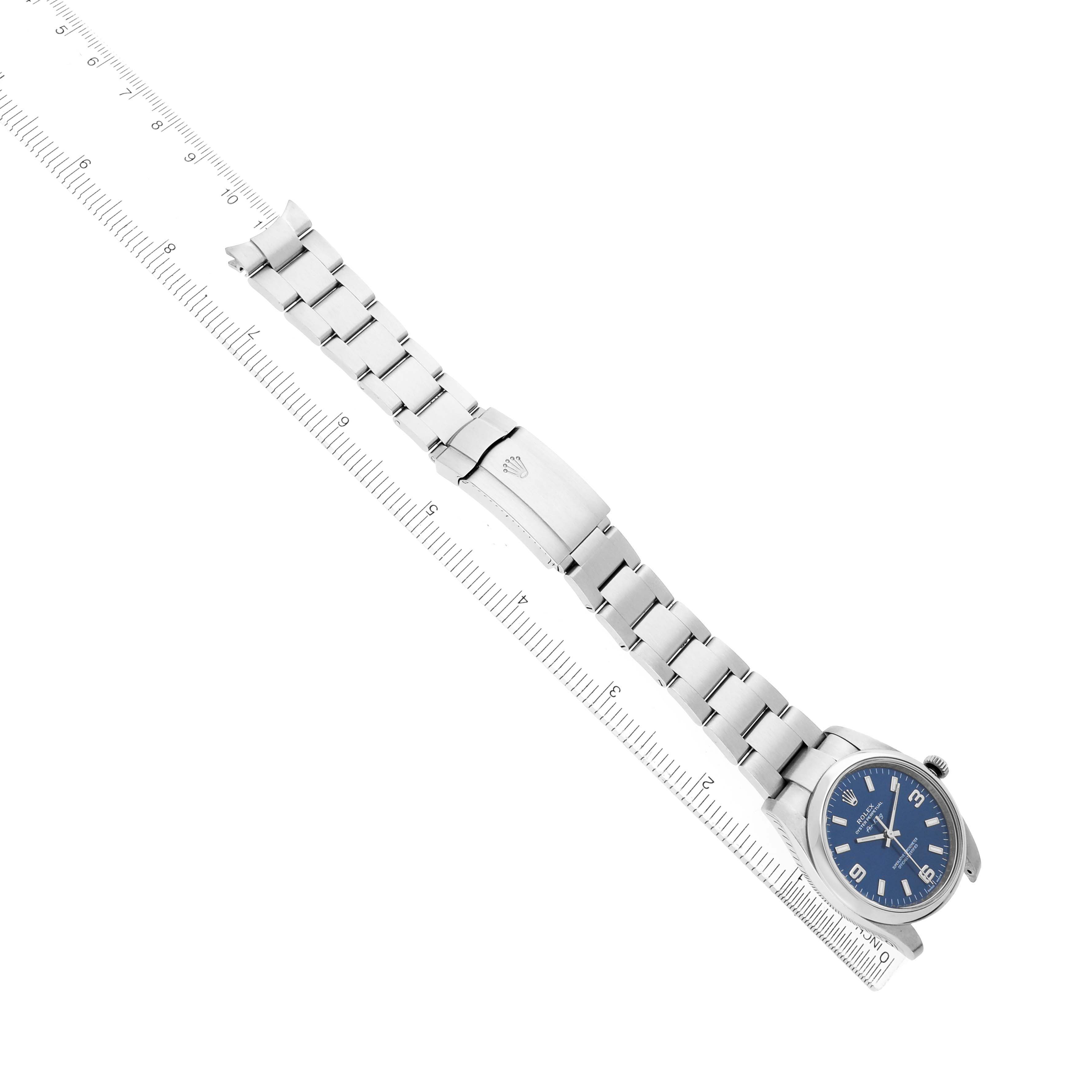 The Rolex Air-King 114200 Men's Stainless Steel Blue Dial watch is displayed at an angle, showing the face, bracelet, and clasp alongside a measuring ruler.