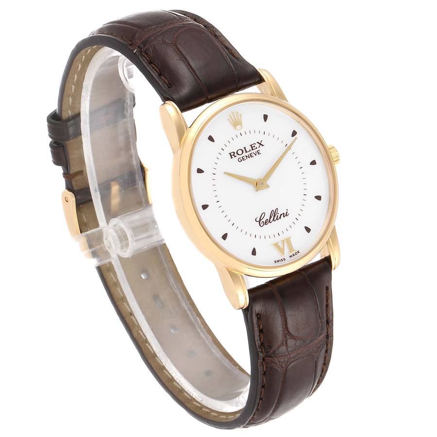 The image shows a side angle of a Rolex Cellini watch, highlighting its white dial, gold case, and brown leather strap.