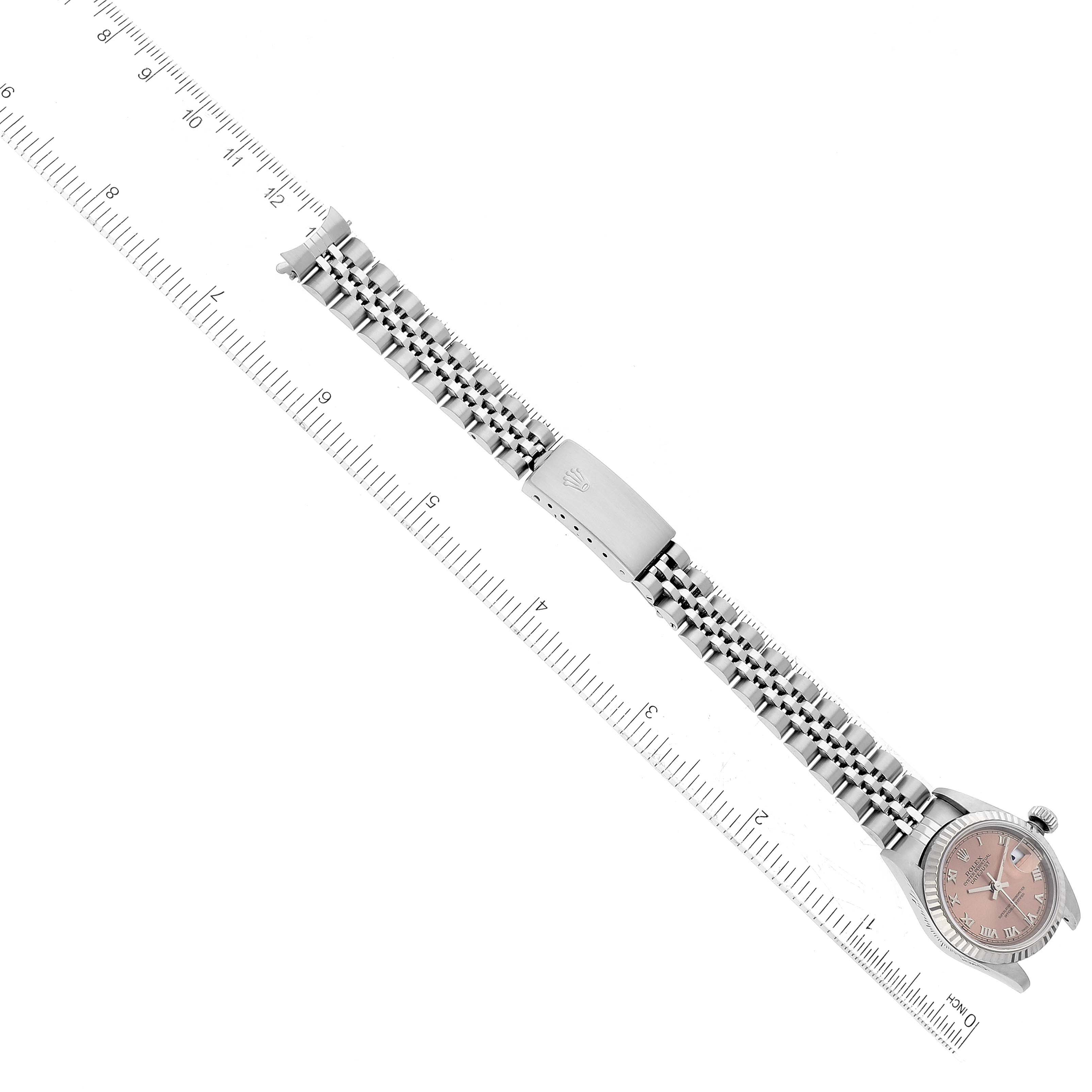 The Rolex Datejust 79174 Women's Stainless Steel Pink Dial 79174 Women's Stainless Steel Pink Dial watch is shown from a top-down angle, focusing on its bracelet and clasp, with a ruler alongside for scale.