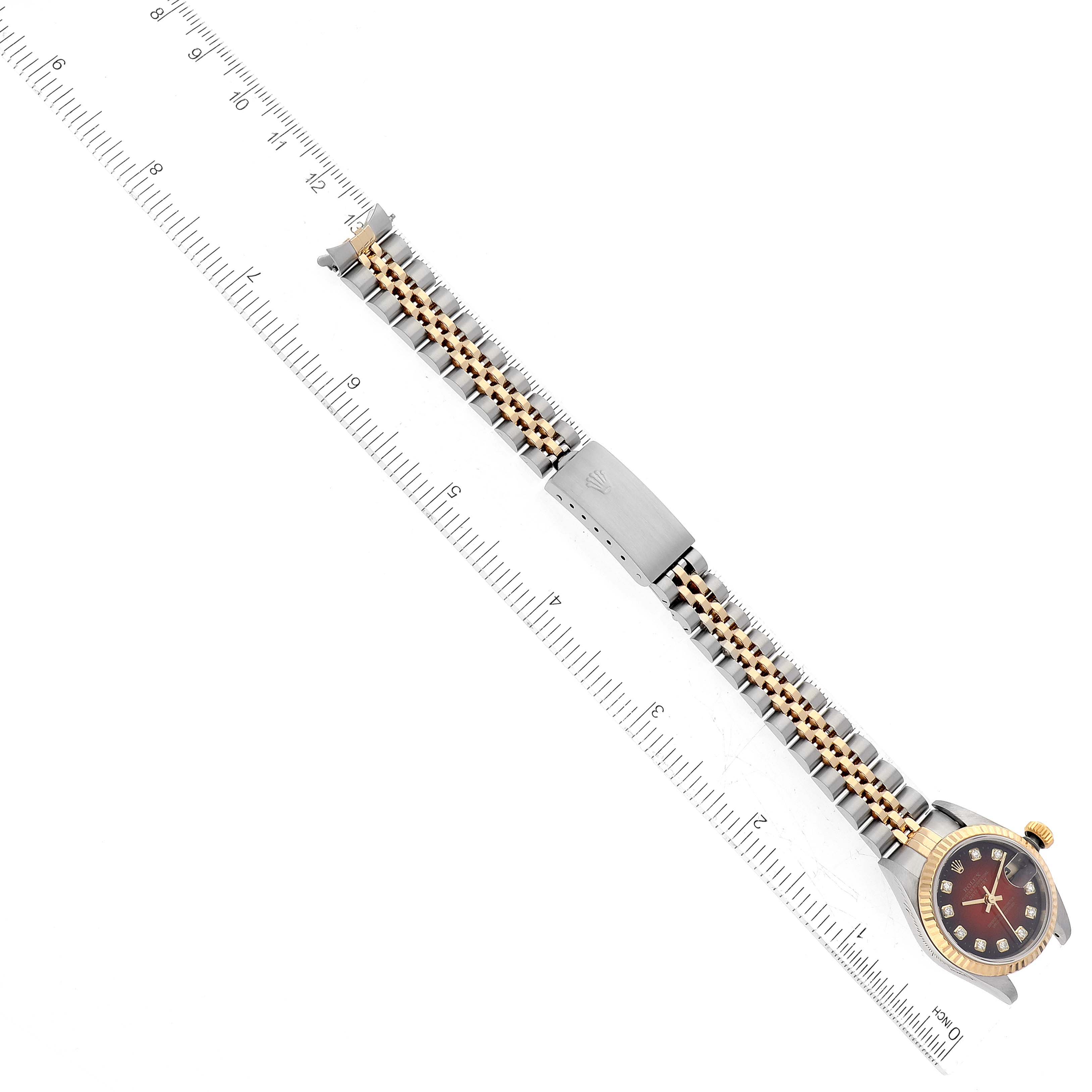 The image shows a Rolex Datejust 79173 Women's Steel and Gold (two tone) Red Dial 79173 Women's Steel and Gold (two tone) Red Dial watch placed horizontally with its full bracelet and a measuring ruler.