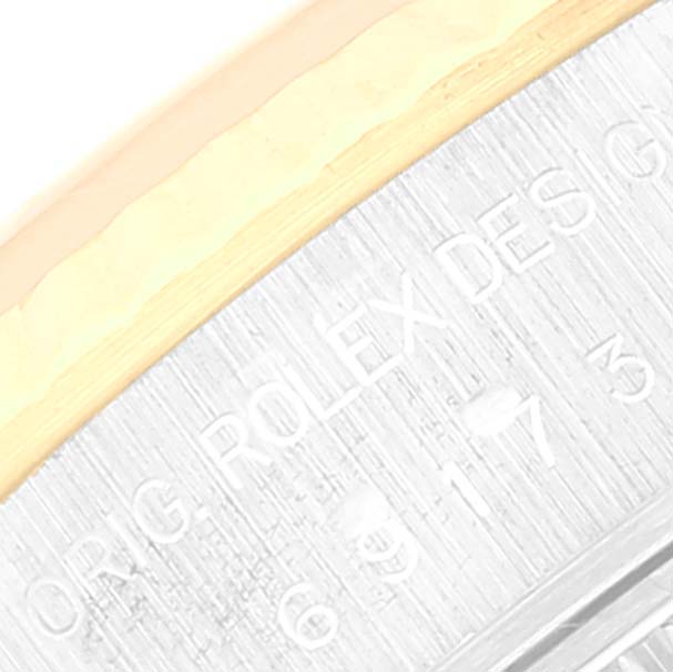 The image shows a close-up of the engraved edge of a Rolex Datejust 69173 Women's Steel and Gold (two tone) Mother of Pearl Dial 69173 Women's Steel and Gold (two tone) Mother of Pearl Dial watch case, highlighting part of the branding and serial number.