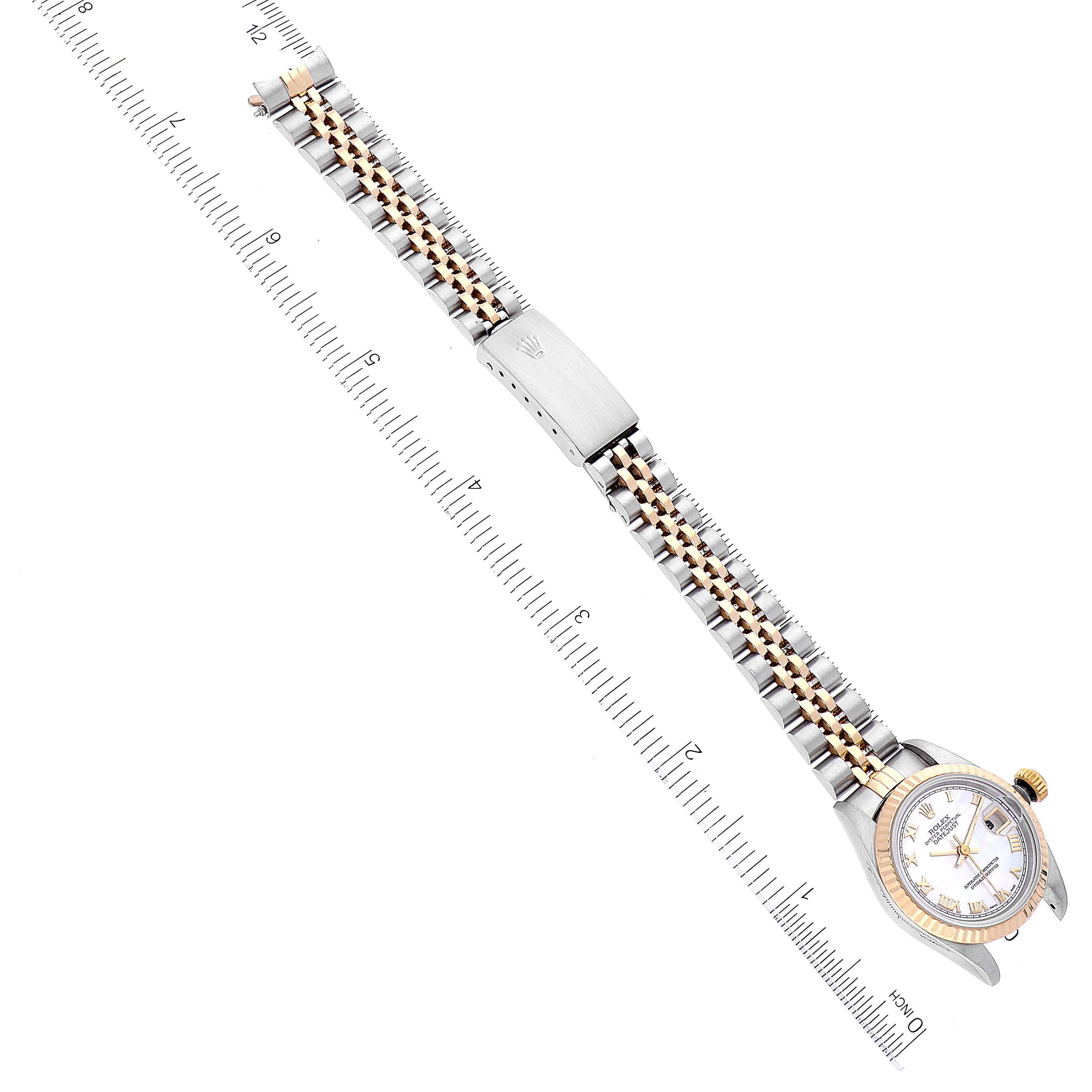 The Rolex Datejust 69173 Women's Steel and Gold (two tone) Mother of Pearl Dial 69173 Women's Steel and Gold (two tone) Mother of Pearl Dial watch is shown from a top-down angle, displaying its face and entire bracelet, with a ruler for scale.