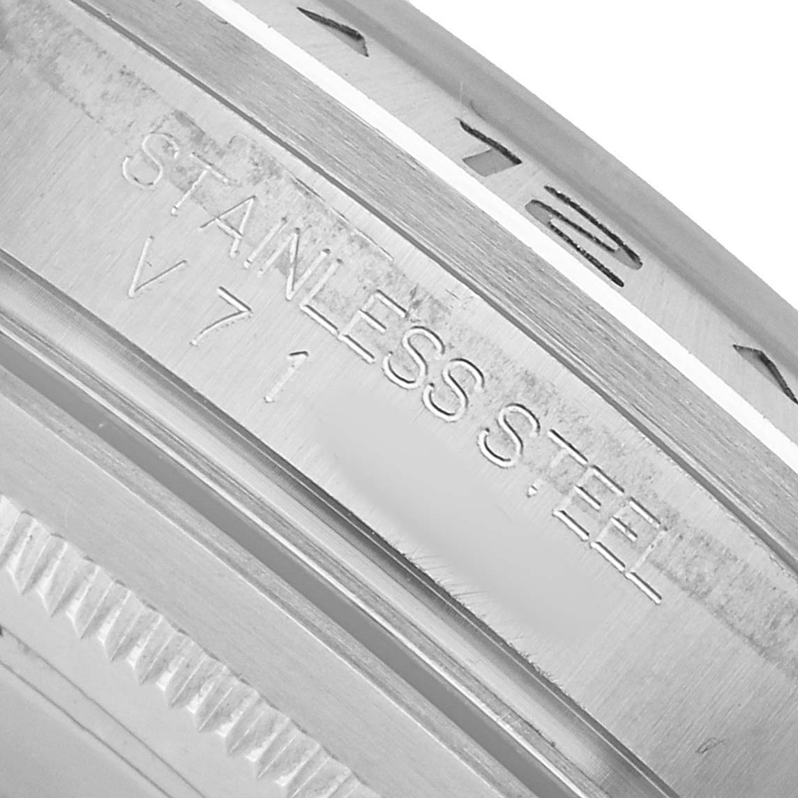The image shows a close-up of the case back edge of a Rolex Explorer 16570 Men's Stainless Steel White Dial, featuring "STAINLESS STEEL" engraving.
