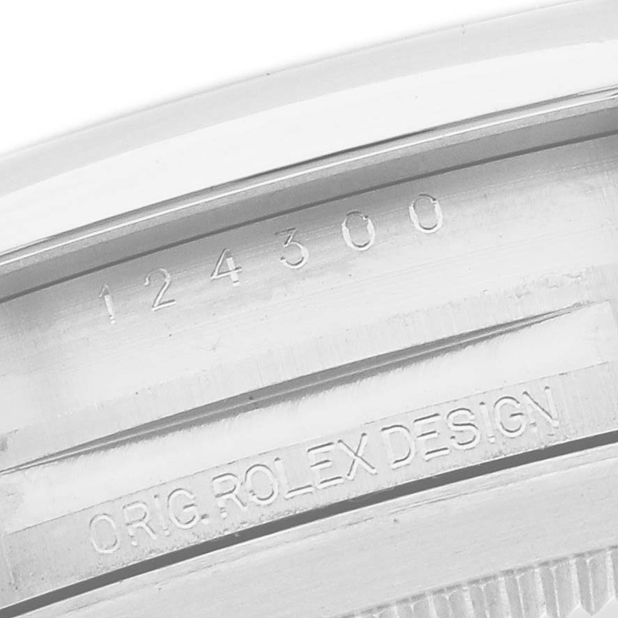 The image shows a close-up of the inner case engraving on a Rolex Oyster Perpetual 124300 Men's Stainless Steel Blue Dial, featuring the model number and "ORIG ROLEX DESIGN."