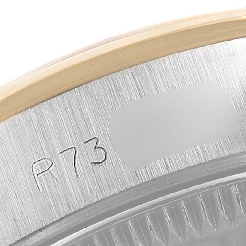 This close-up image displays the side of the bezel and part of the case of a Rolex Oyster Perpetual 67183 Women
s Steel and Gold (two tone) Champagne Dial 67183 Women
s Steel and Gold (two tone) Champagne Dial watch, showing engraved details.