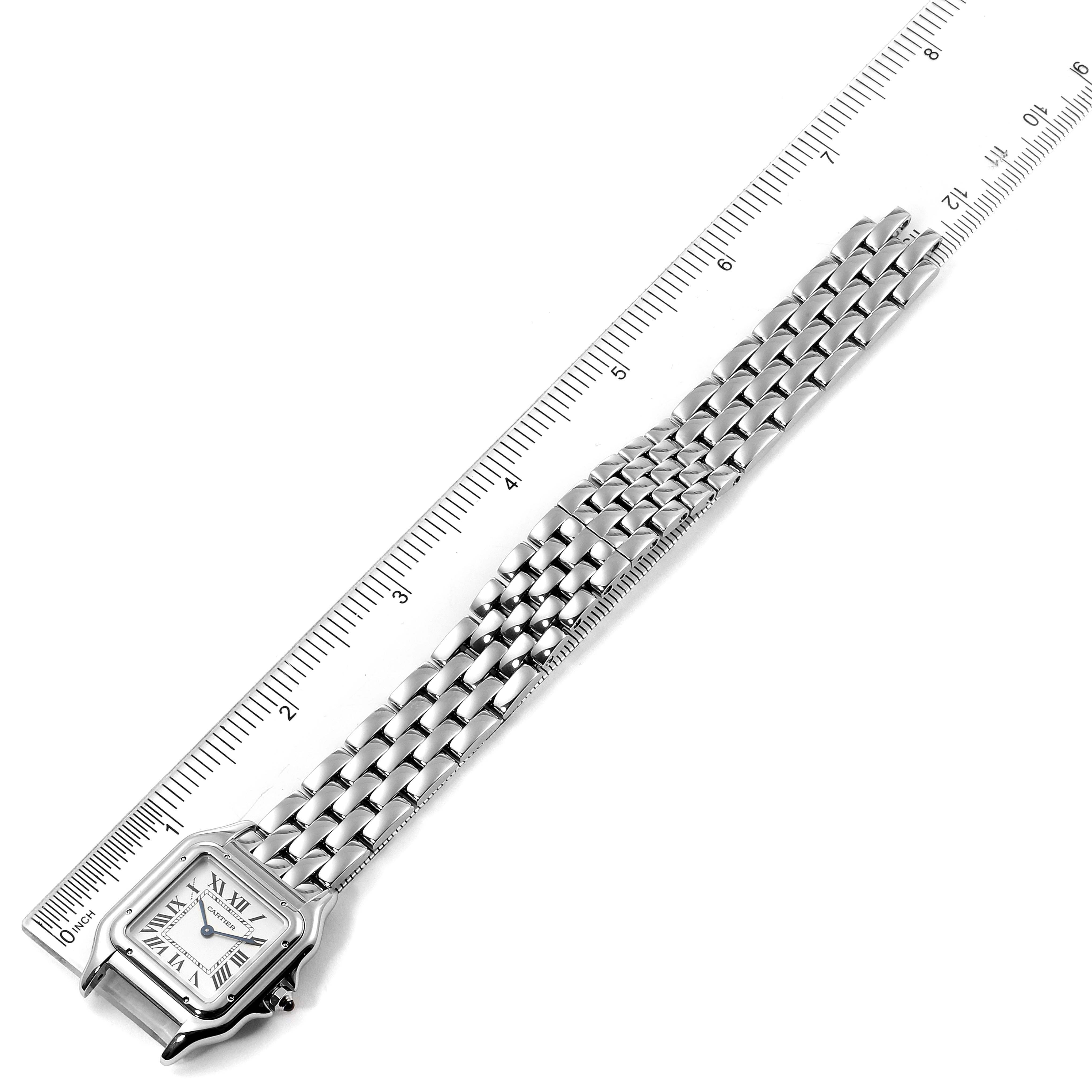 The image shows the Cartier Panthere WSPN0007 Women
s Stainless Steel Silver Dial WSPN0007 Women
s Stainless Steel Silver Dial watch from a top-down angle, displaying the face and metal bracelet strap beside a ruler.