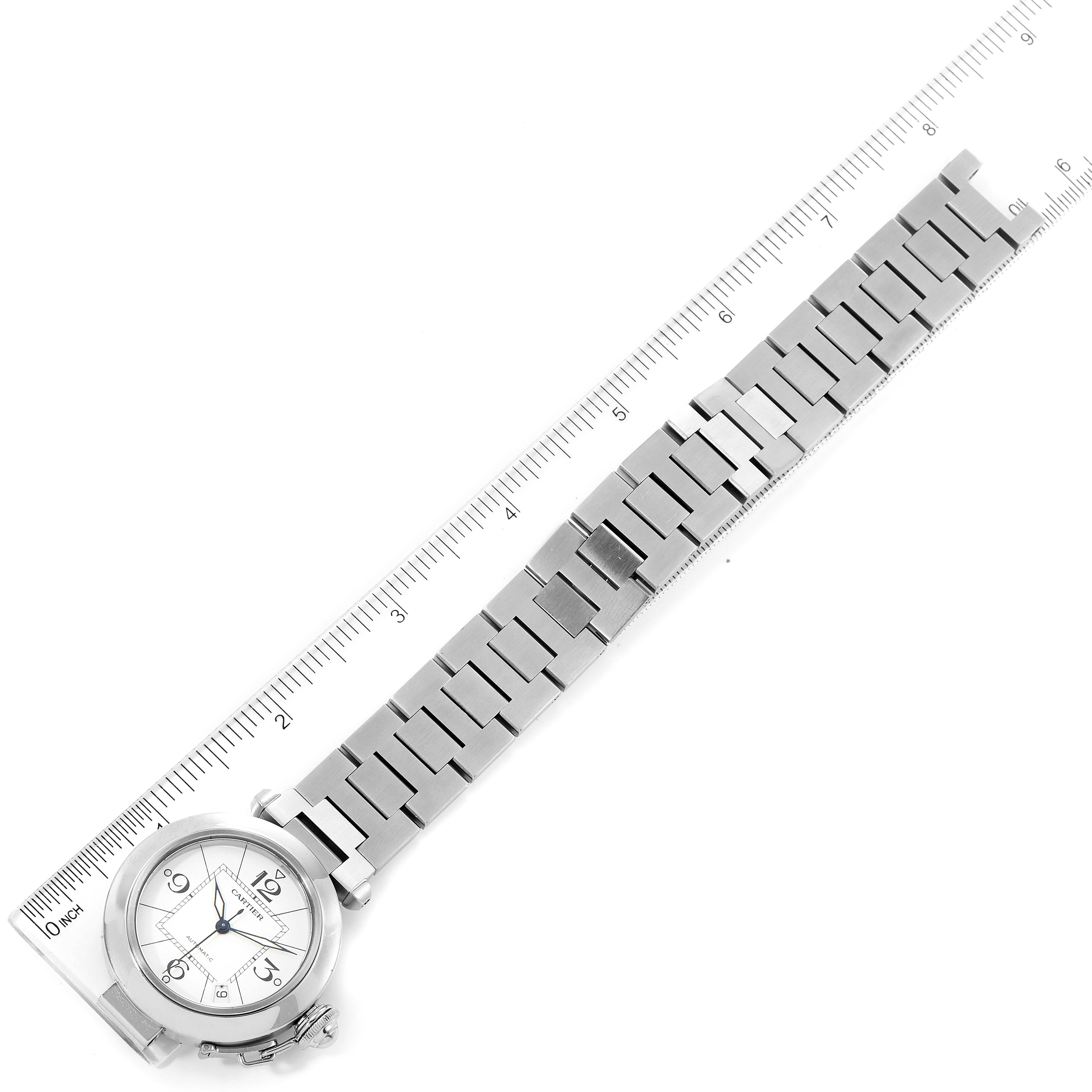 The Cartier Pasha W31074M7 Men's Stainless Steel White Dial W31074M7 Men's Stainless Steel White Dial watch is shown from a top-down angle, displaying the face, bezel, and entire metal bracelet alongside a ruler for scale.