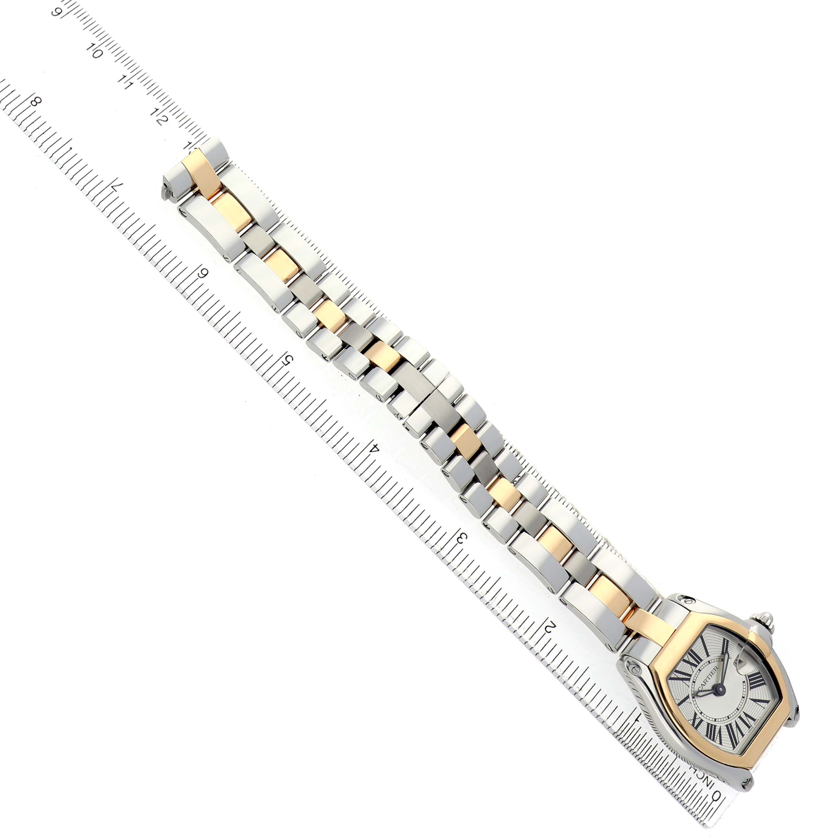 The Cartier Roadster W62026Y4 Women's Steel and Gold (two tone) Silver Dial watch is shown at an angle, displaying the case and bracelet alongside a ruler.