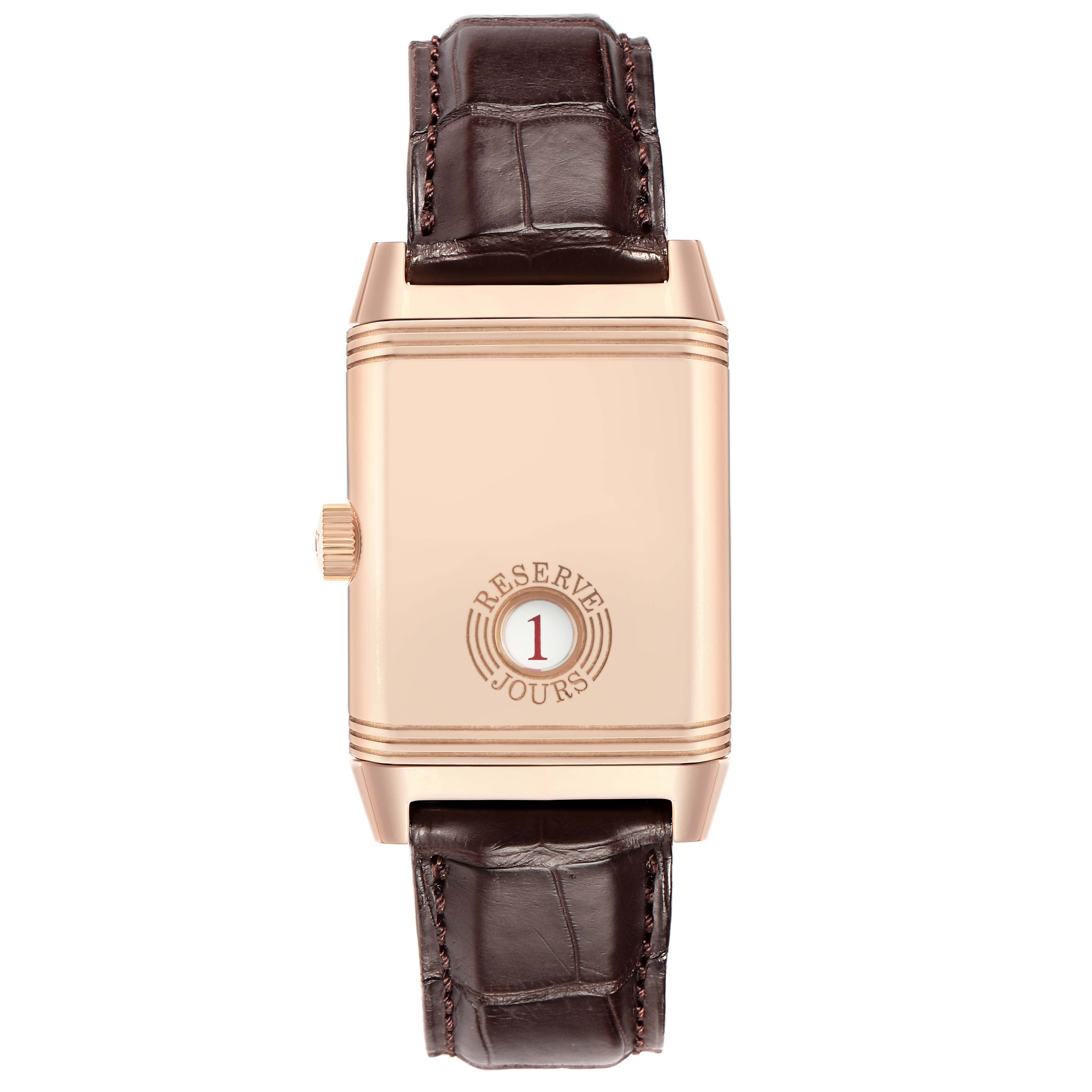 The image shows the back of a Jaeger-LeCoultre Reverso watch with a visible crown and leather straps.