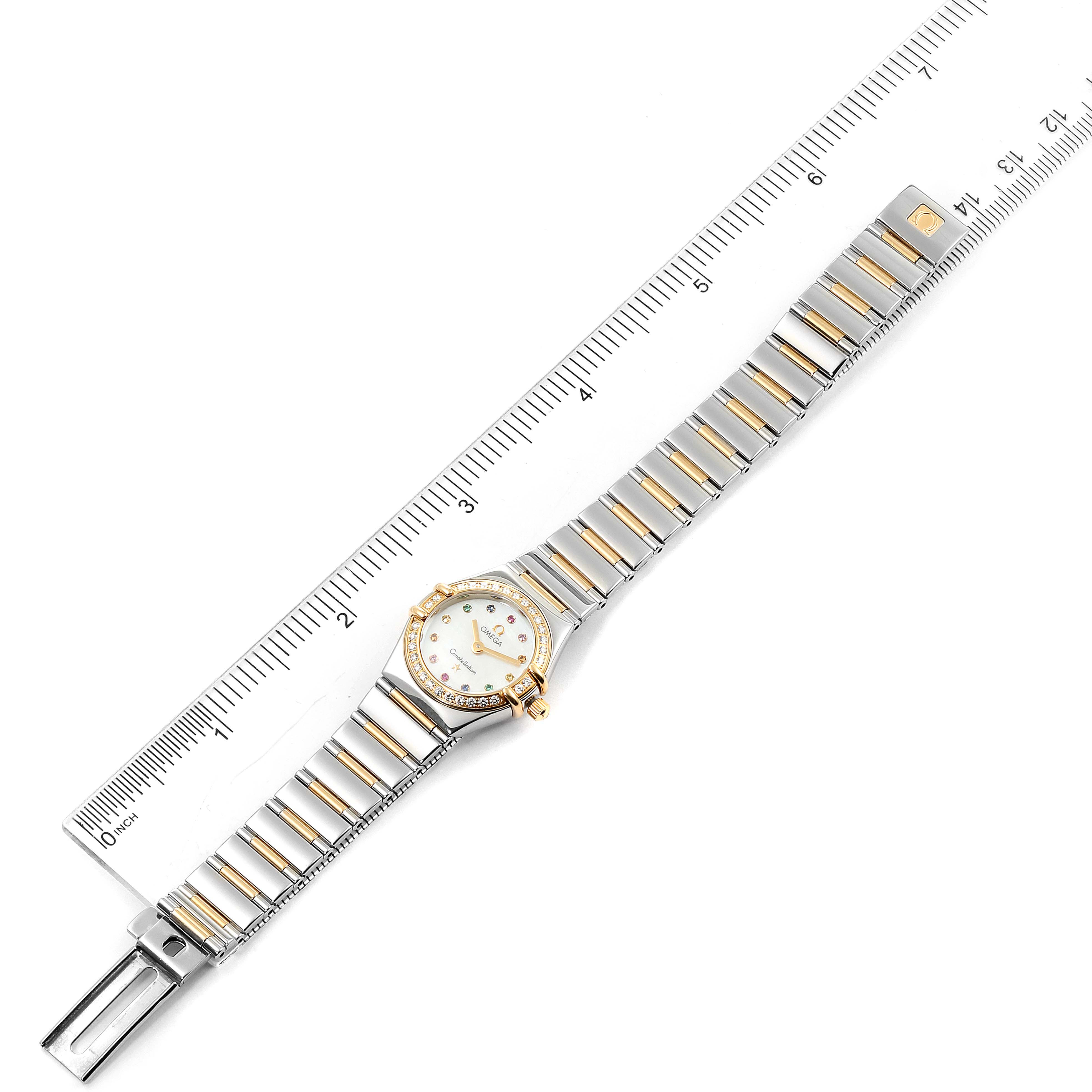 The image shows an Omega 1365.79.00 Women's Stainless Steel Mother of Pearl Dial 1365.79.00 Women's Stainless Steel Mother of Pearl Dial Constellation Iris Steel Yellow Gold Multi Stone Watch (model 1365.79.00) placed alongside a ruler, showing the entire watch and bracelet from a flat perspective.