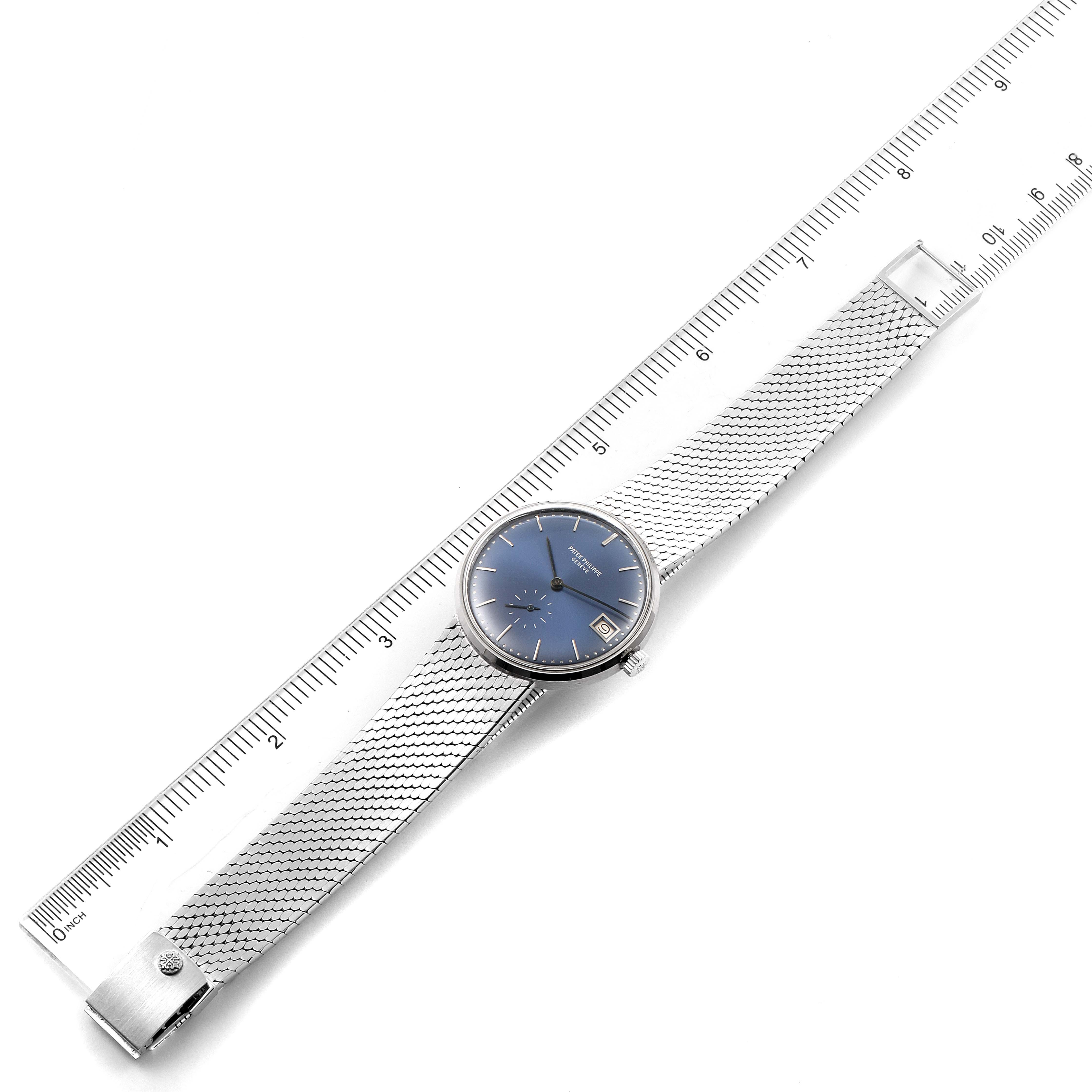 This is a top-down view of a Vintage Patek Philippe watch with a silver mesh band and a blue dial, next to a ruler for scale.