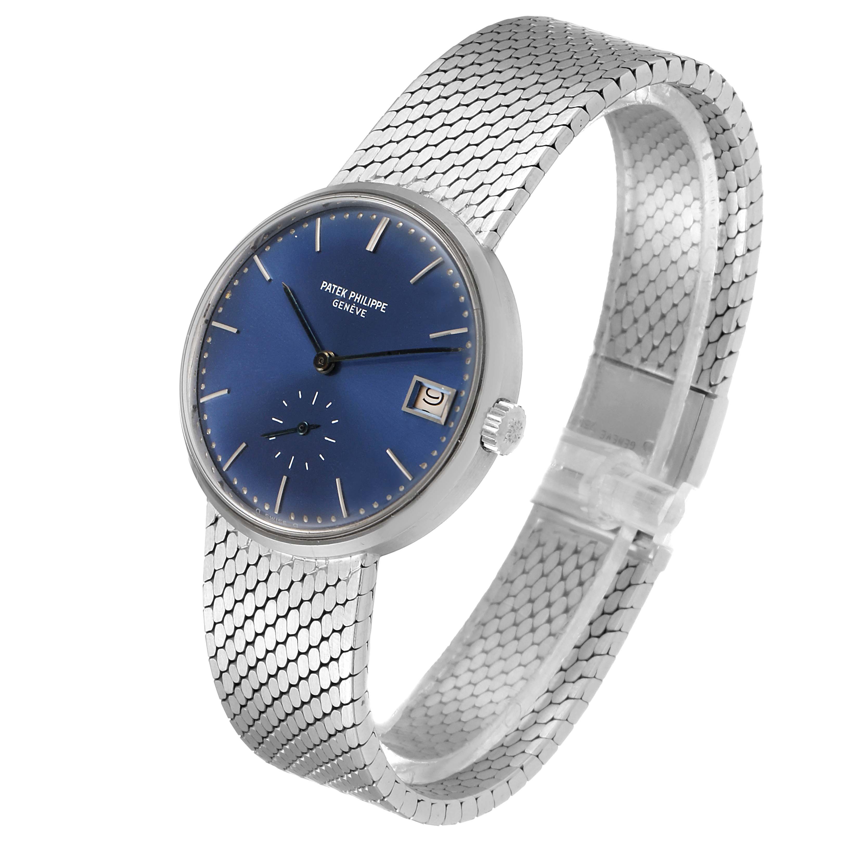 This image shows a Patek Philippe Vintage watch at a three-quarter angle, displaying its blue dial, mesh bracelet, and date window.