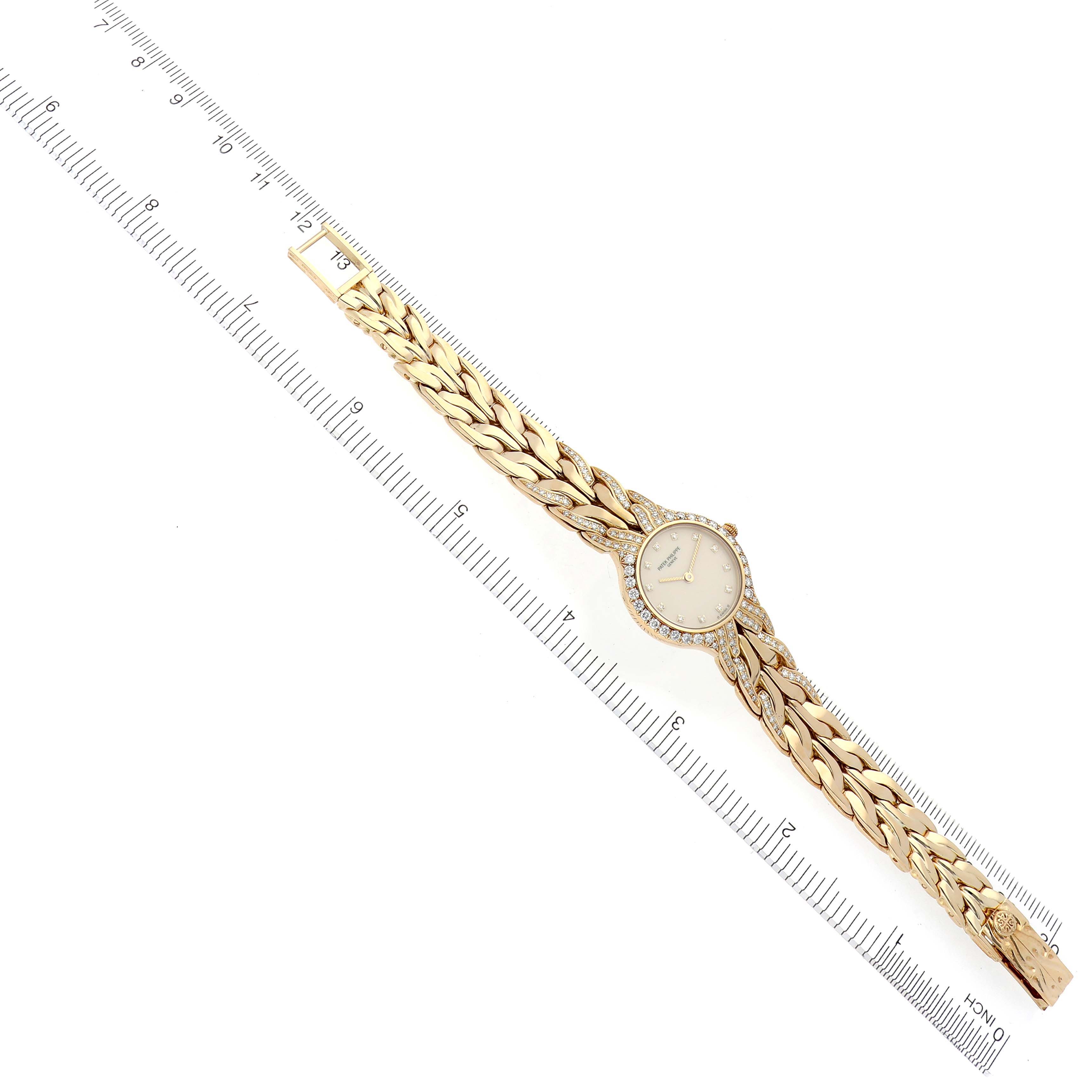 The Patek Philippe La Flamme  4816/3J Women's Yellow Gold Champagne Dial 4816/3J Women's Yellow Gold Champagne Dialwatch is shown from an overhead angle, displaying its face and decorative band alongside a ruler.