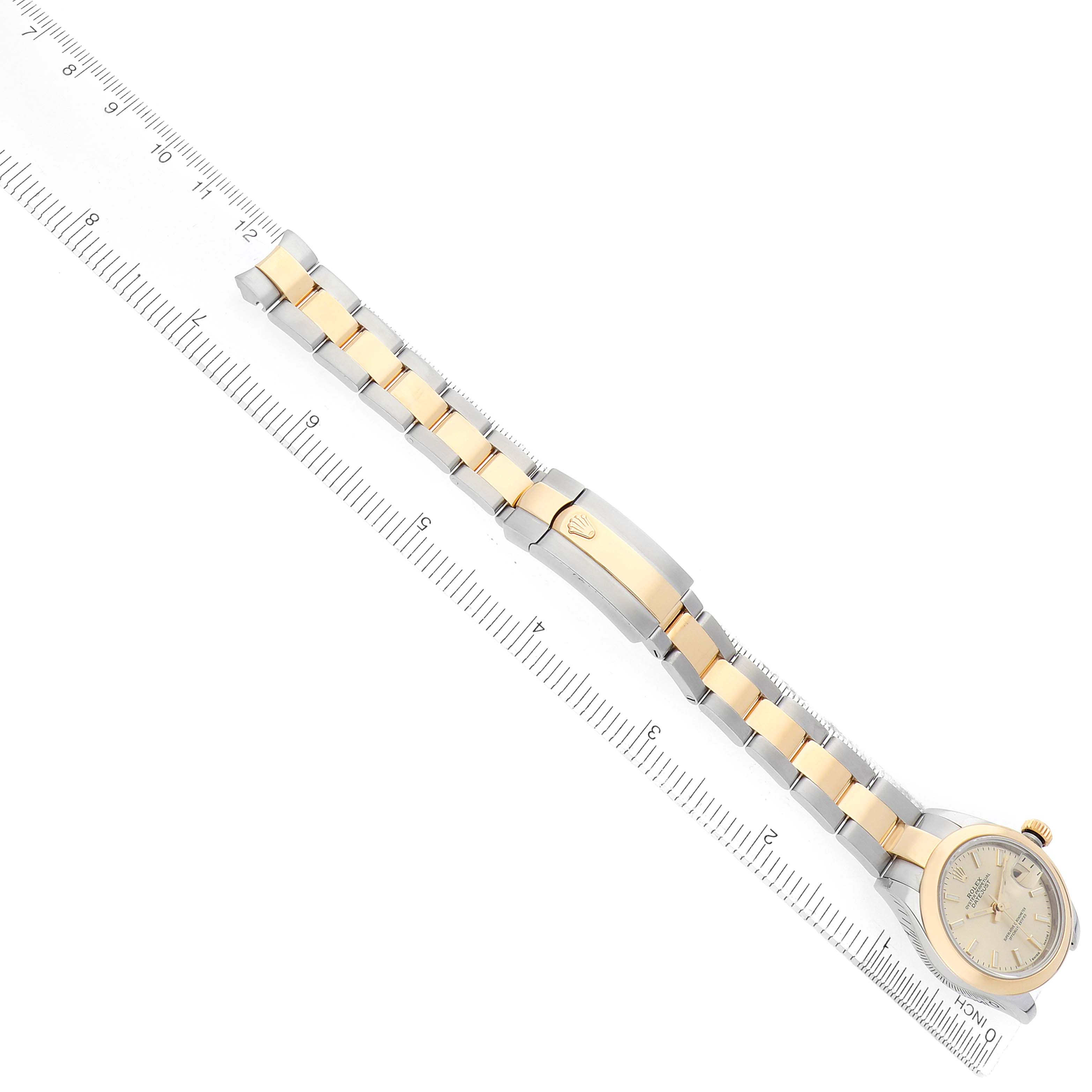 The Rolex Datejust 279163 Women's Steel and Gold (two tone) Champagne Dial watch is displayed diagonally, showing the full bracelet, clasp, and face, with a ruler for scale.