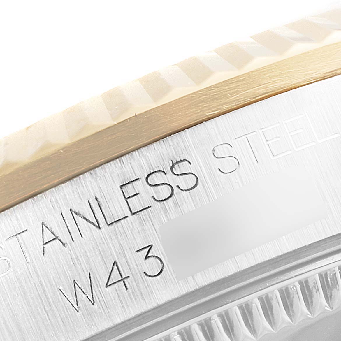 This close-up image shows the side of the bezel and part of the stainless steel back of a Mid-Size Rolex watch.