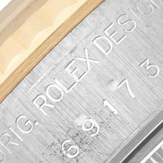 The image shows a close-up of the case side of a Rolex Datejust 69173 Women's Steel and Gold (two tone) White Dial 69173 Women's Steel and Gold (two tone) White Dial, highlighting engraved text and design details.