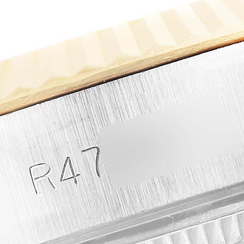 The image shows a close-up of the side engraving and fluted bezel of a Rolex Datejust 69173 Women's Steel and Gold (two tone) White Dial 69173 Women's Steel and Gold (two tone) White Dial watch.