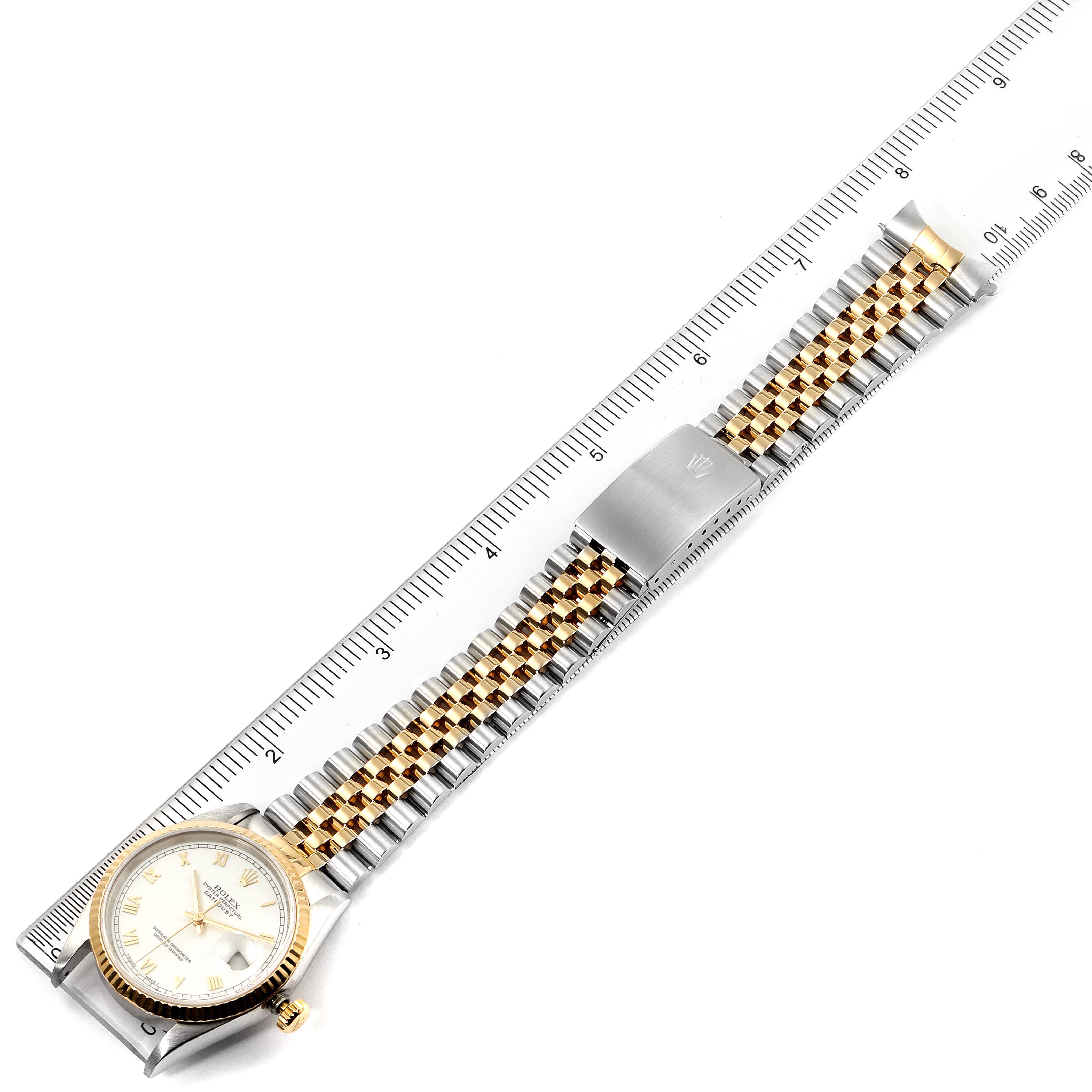 This image shows a Rolex Datejust 16233 Men's Steel and Gold (two tone) White Dial 16233 Men's Steel and Gold (two tone) White Dial watch laid flat, highlighting its bracelet, clasp, and face, along with a ruler for scale.
