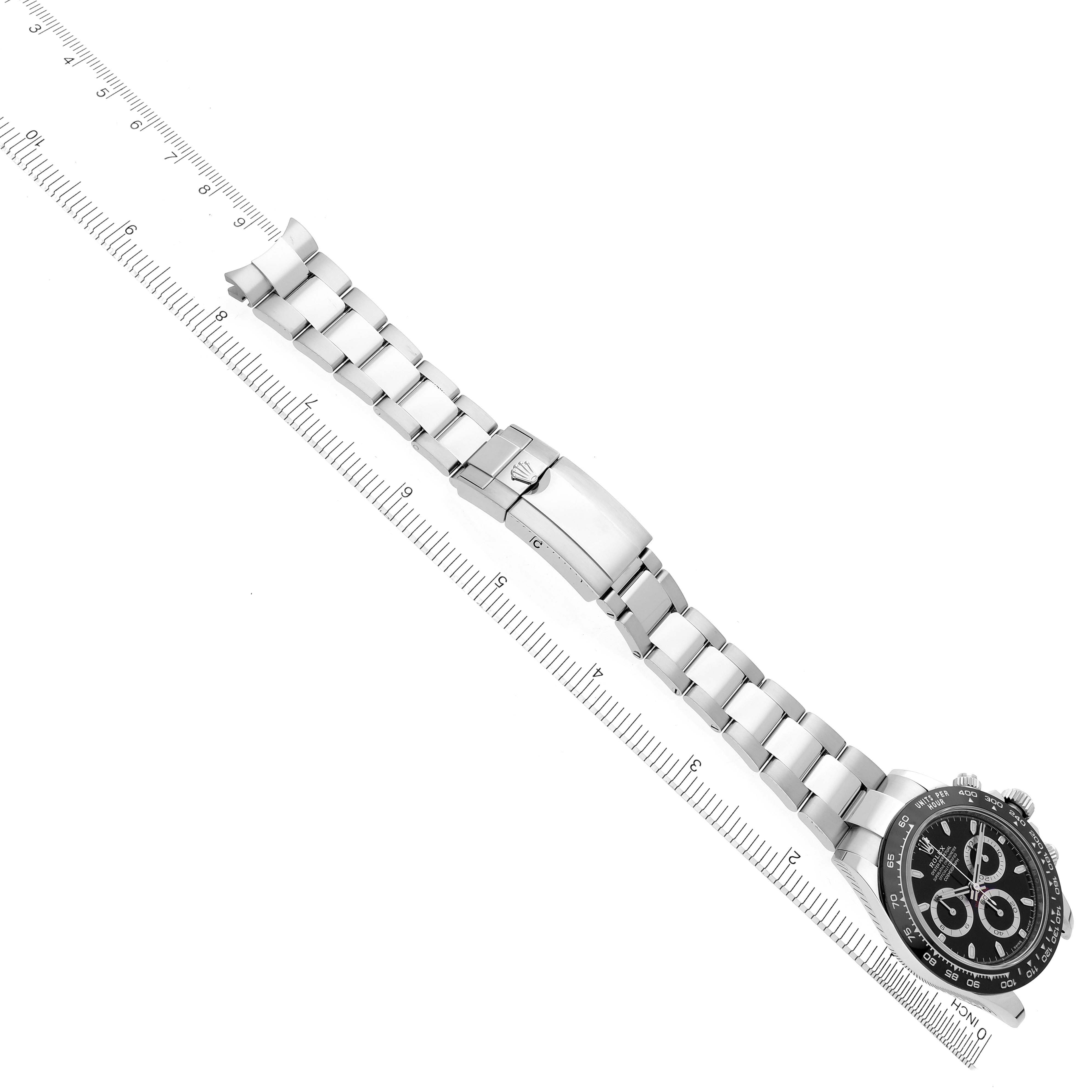 The image shows a top-down angle of a Rolex Daytona 116500LN Men's Stainless Steel Black Dial 116500LN Men's Stainless Steel Black Dial watch with its full strap and clasp visible alongside a ruler.