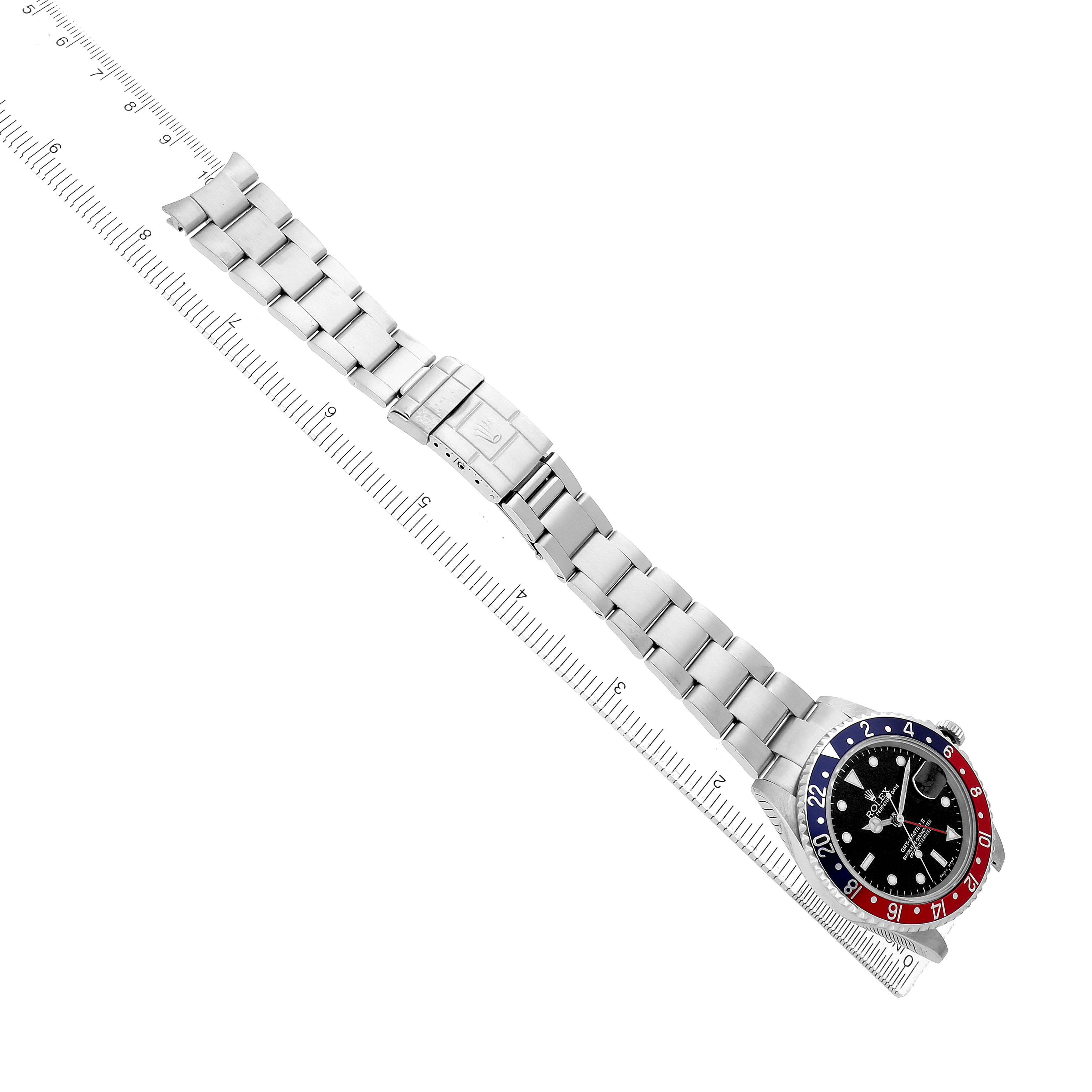 The Rolex GMT-Master 16710 Men's Stainless Steel Black Dial watch is shown at an angled top view, displaying the bezel, dial, and bracelet alongside a measuring ruler.