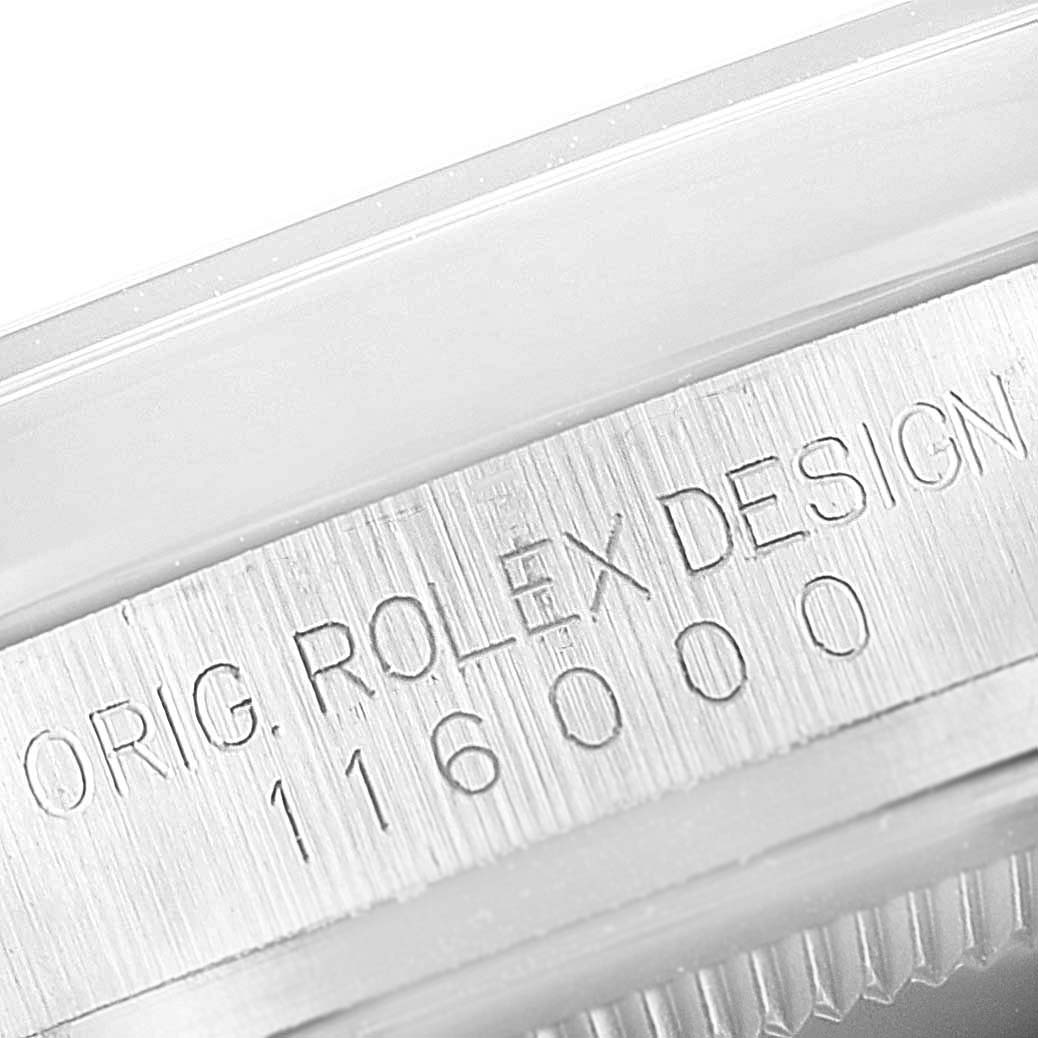 The image shows a close-up of the engraved inner bezel of a Rolex Oyster Perpetual 116000 Men's Stainless Steel Black Dial watch.