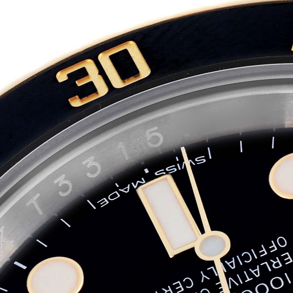 The image shows a close-up of the Rolex Submariner 116613LN Men's Steel and Gold (two tone) Black Dial 116613LN Men's Steel and Gold (two tone) Black Dial's bezel and part of its dial with markers.