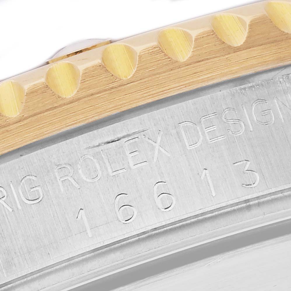 The image shows a close-up of the Rolex Submariner 16613 Men
s Steel and Gold (two tone) Black Dial 16613 Men
s Steel and Gold (two tone) Black Dial
s engraved case and the edge of the bezel.