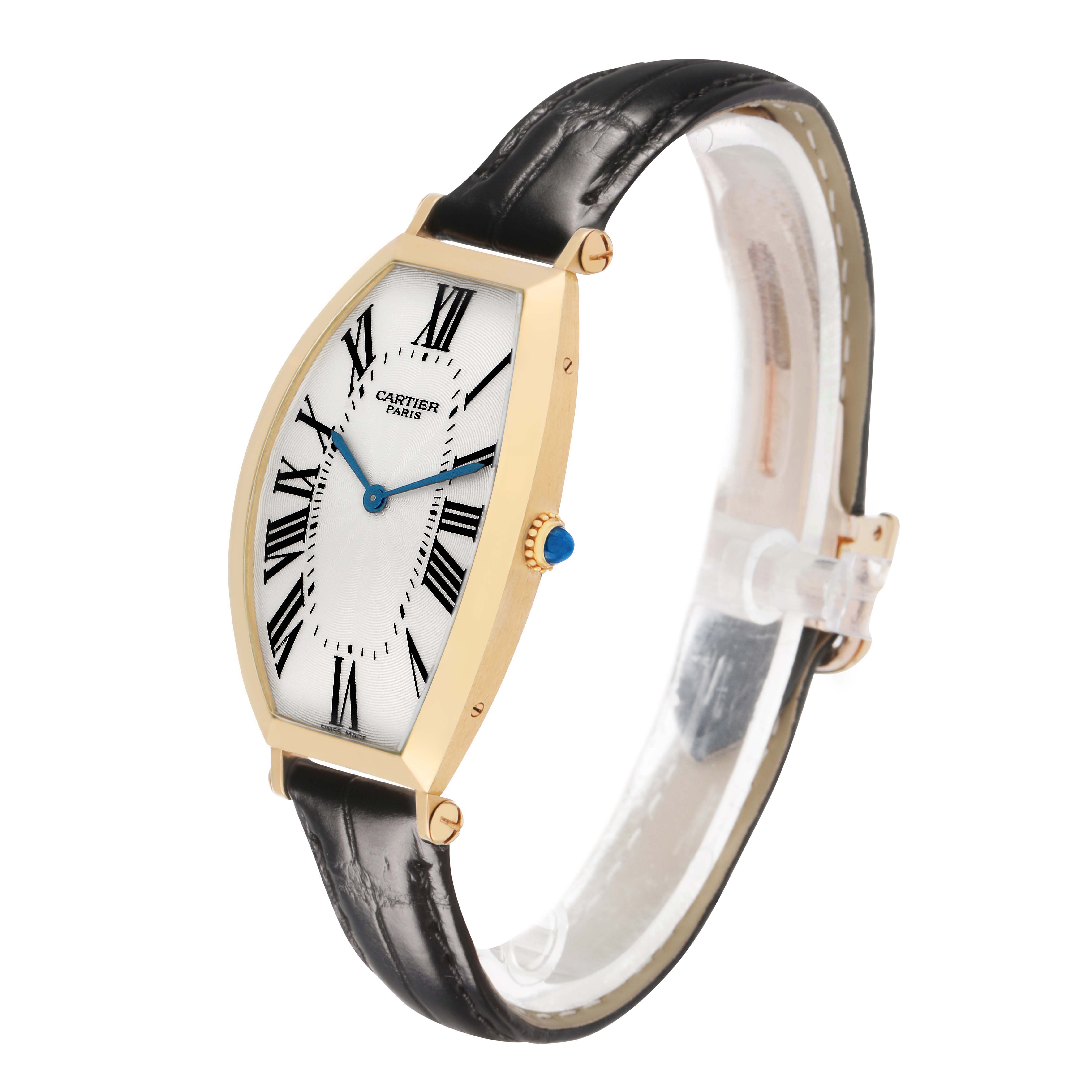 The Cartier Tonneau W1527651F Men's Yellow Gold Silver Dial watch is shown at an angled side view, displaying its gold case, Roman numeral dial, black strap, and crown.