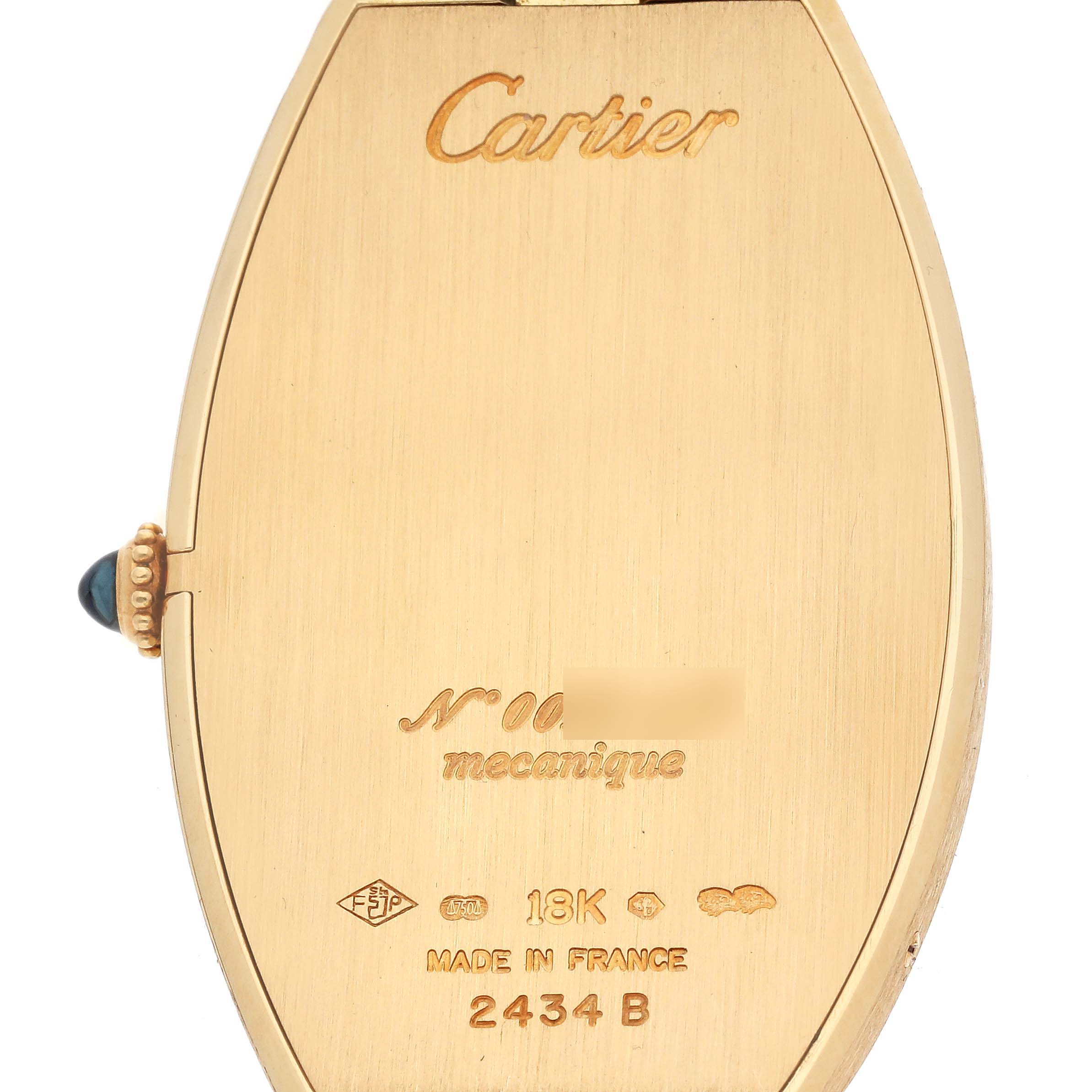 The image shows the back of the Cartier Tonneau W1527651F Men's Yellow Gold Silver Dial model watch, highlighting engravings and the crown with a cabochon.
