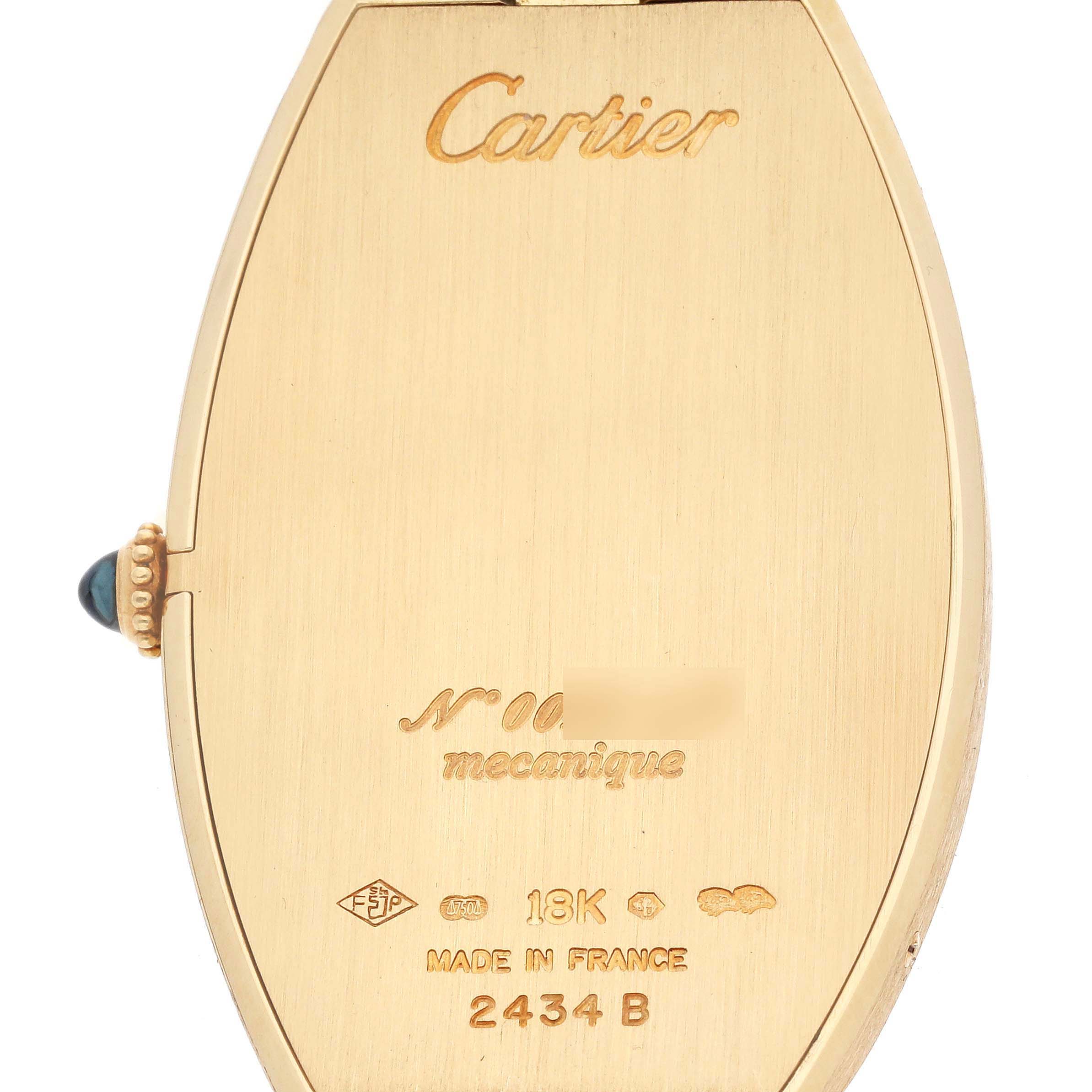 The image shows the back of a Cartier Tonneau W1527651F Men's Yellow Gold Silver Dial watch, highlighting its gold case and inscriptions.