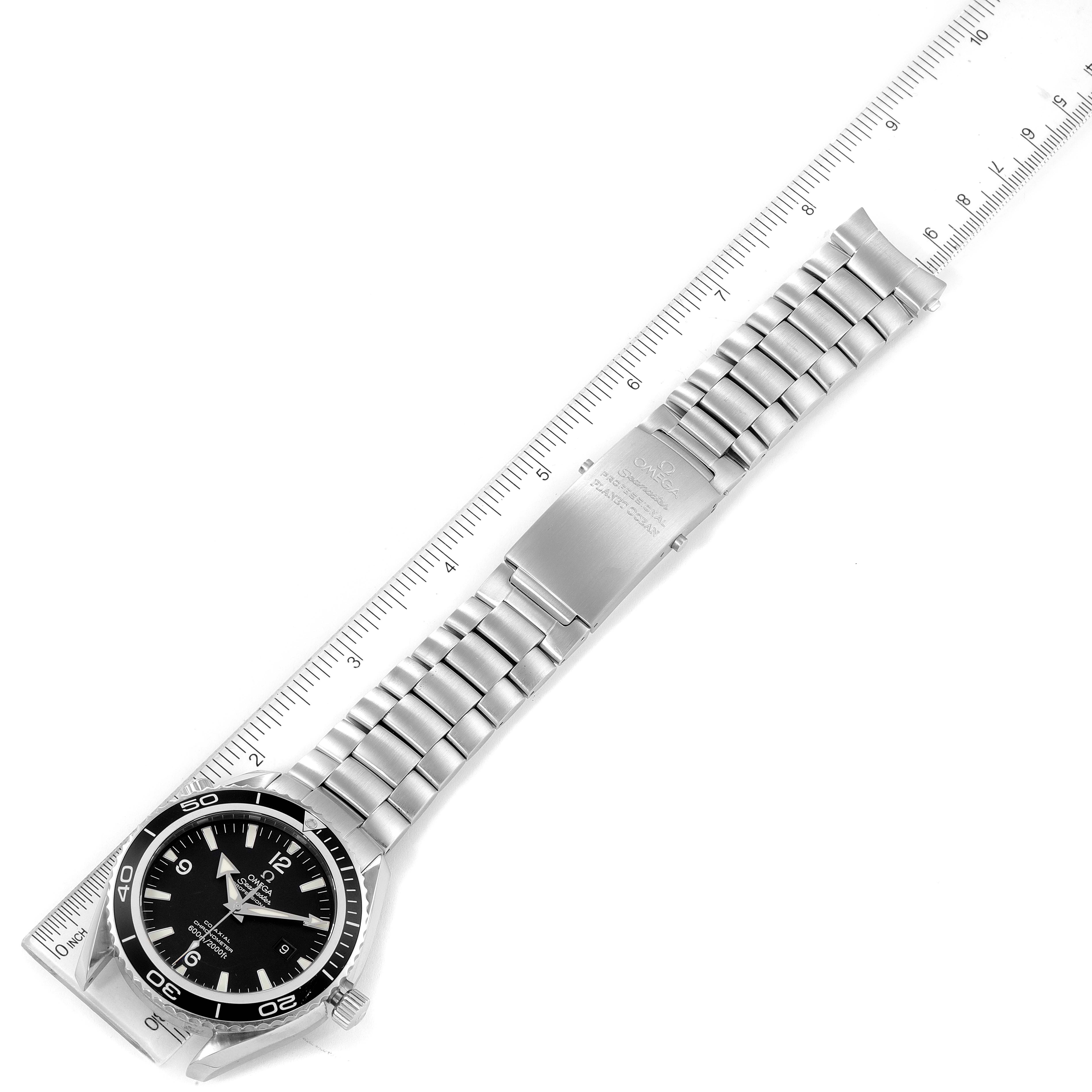 The image shows the Omega Planet Ocean 2200.50.00 Men's Stainless Steel Black Dial 2200.50.00 Men's Stainless Steel Black Dial watch laid flat, highlighting its face, bezel, and full metal bracelet with a ruler for scale.