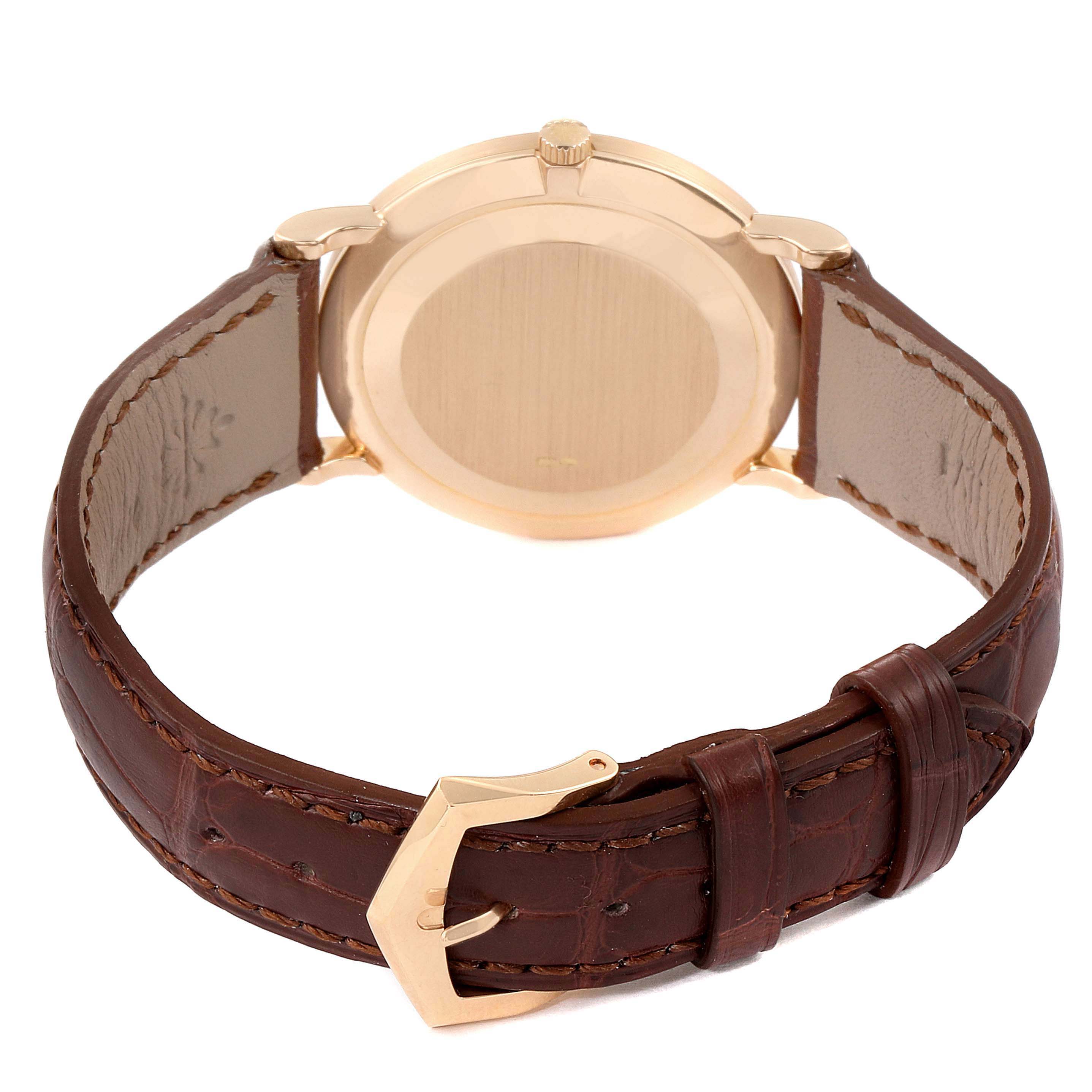 The image shows the back view of a Patek Philippe Calatrava 3919R Men
s Rose Gold White Dial 3919R Men
s Rose Gold White Dial watch, featuring its case back, crown, and brown leather strap with a buckle.